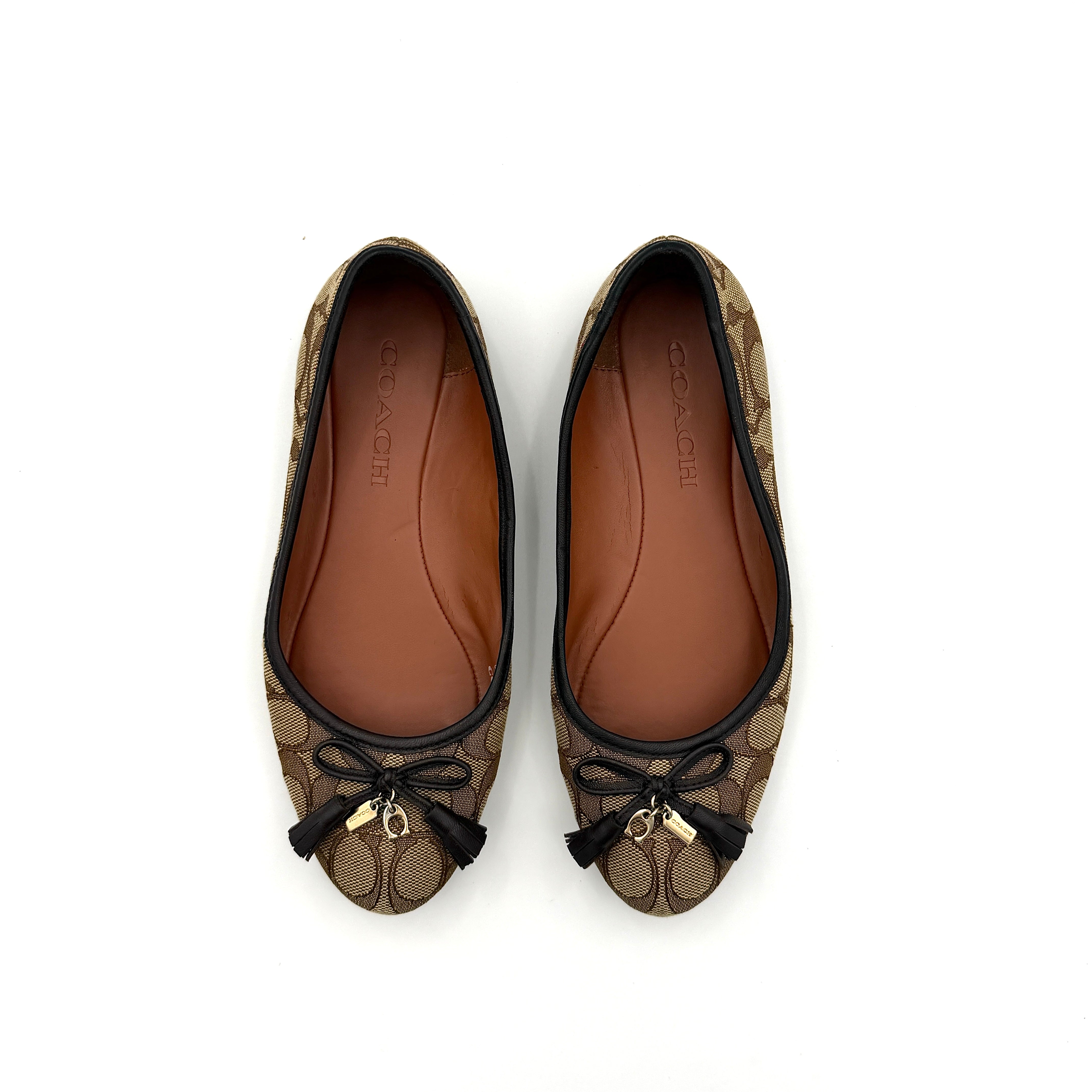 Coach Signature Bennie Jacqueline ballet flats in beige canvas with brown leather trims, shown side by side with tassel and gold charm details.