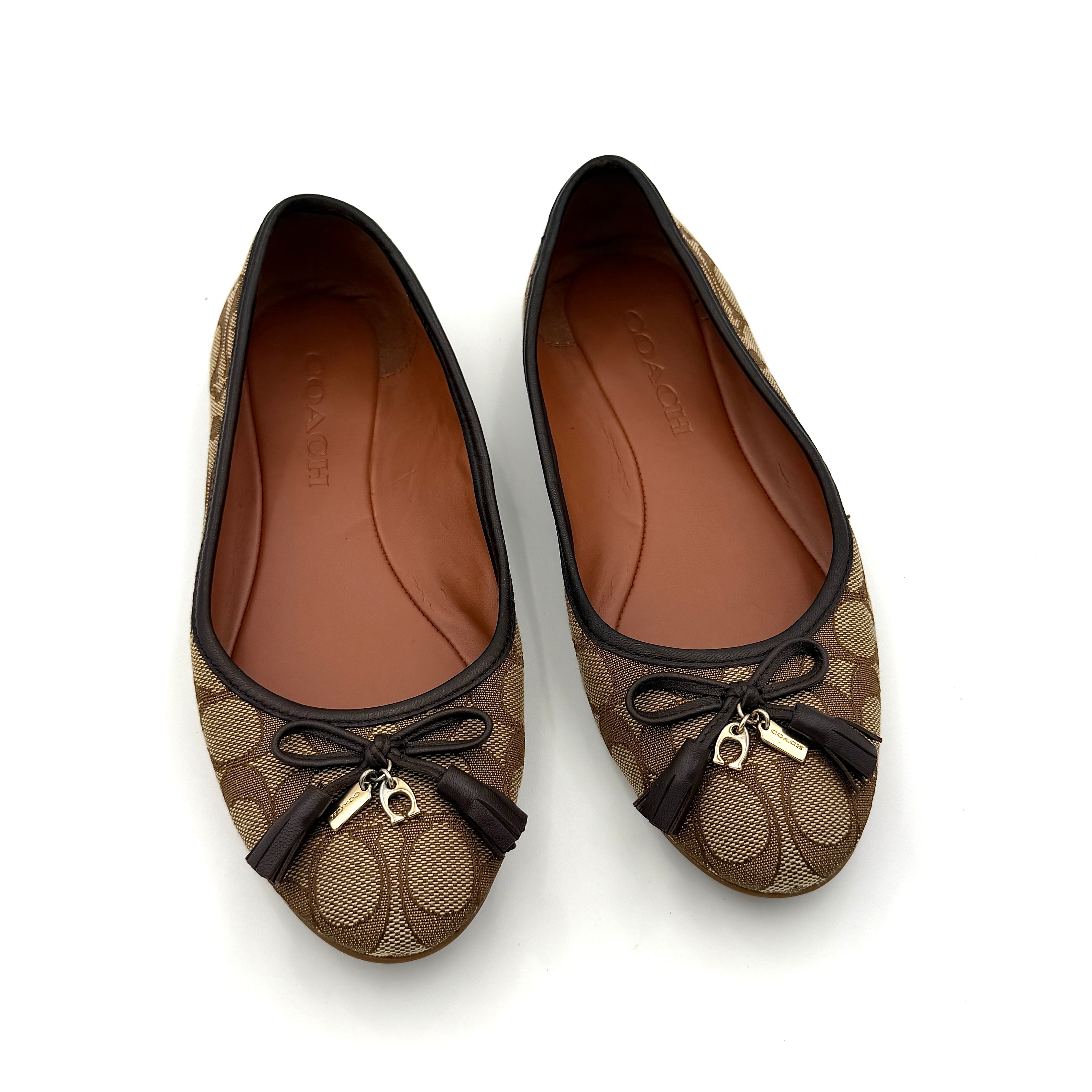 Coach Signature Bennie Jacqueline ballet flats in beige canvas with brown leather trims, shown side by side with tassel and gold charm details.