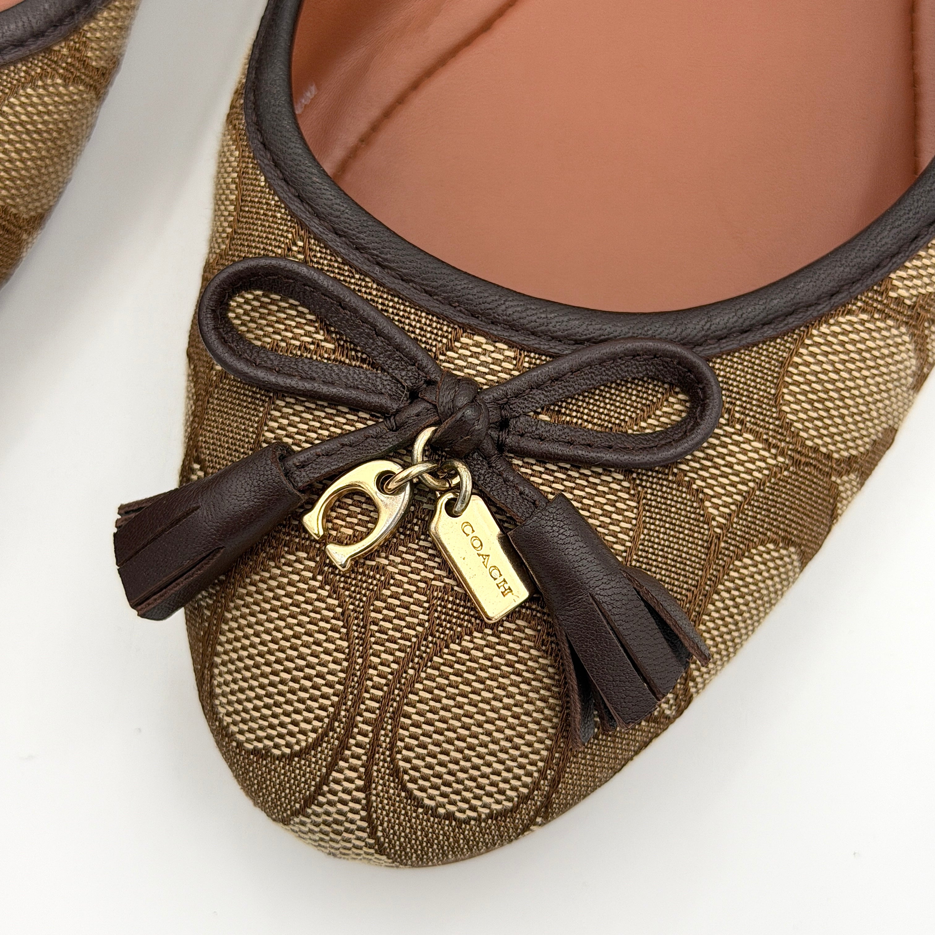 Coach Signature Bennie Jacqueline ballet flats in beige canvas with brown leather trims, shown side by side with tassel and gold charm details.