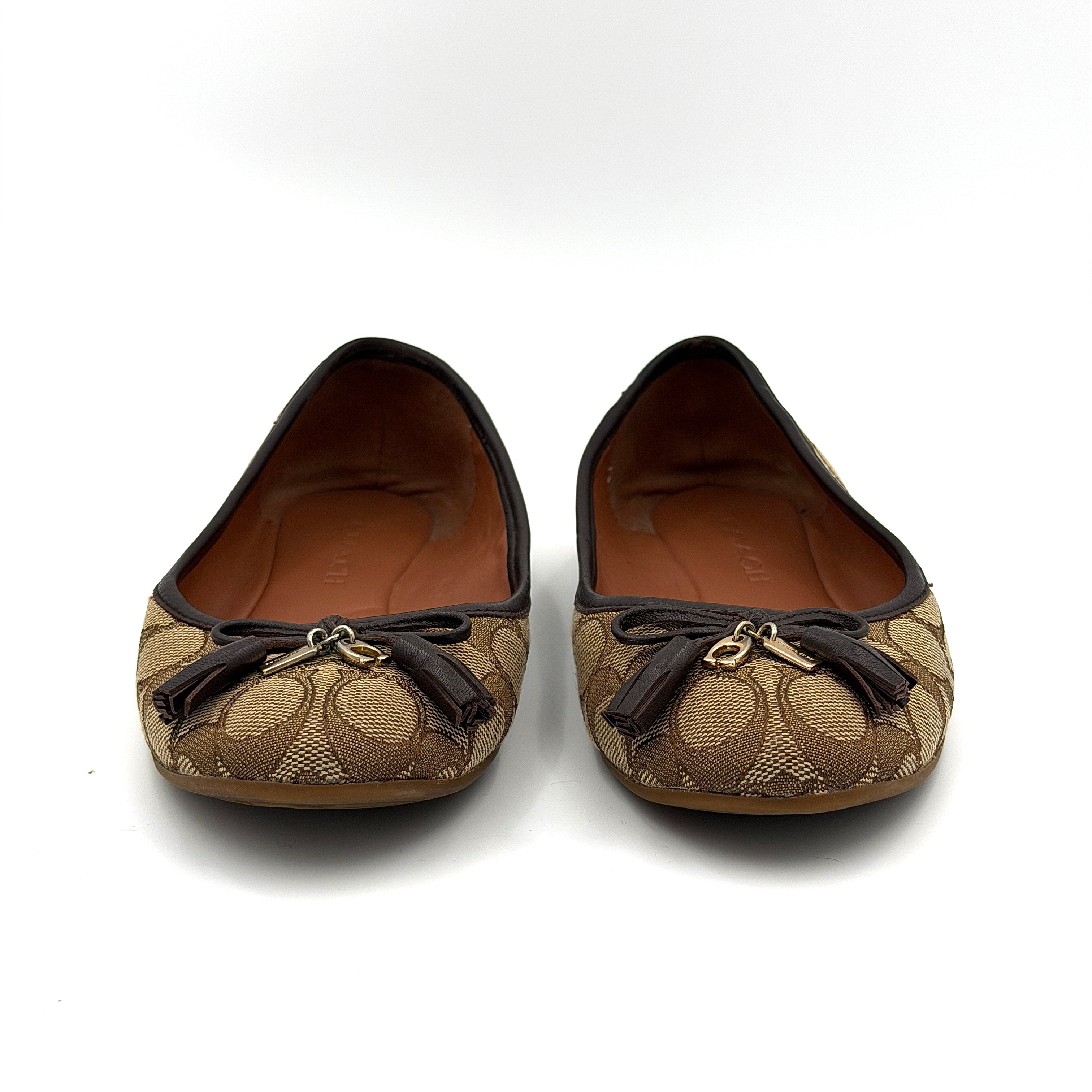Coach Signature Bennie Jacqueline ballet flats in beige canvas with brown leather trims, shown side by side with tassel and gold charm details.
