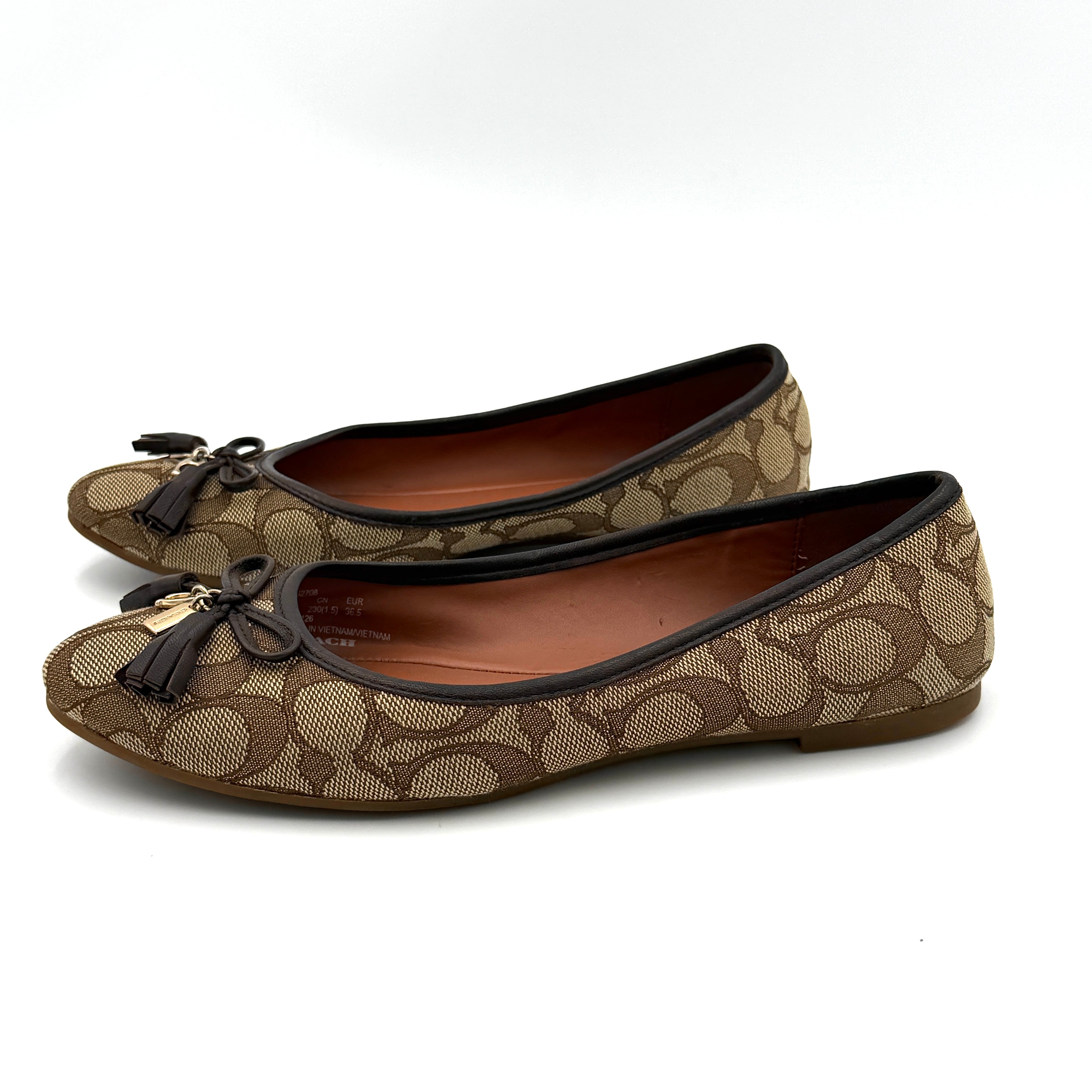 Coach Signature Bennie Jacqueline ballet flats in beige canvas with brown leather trims, shown side by side with tassel and gold charm details.