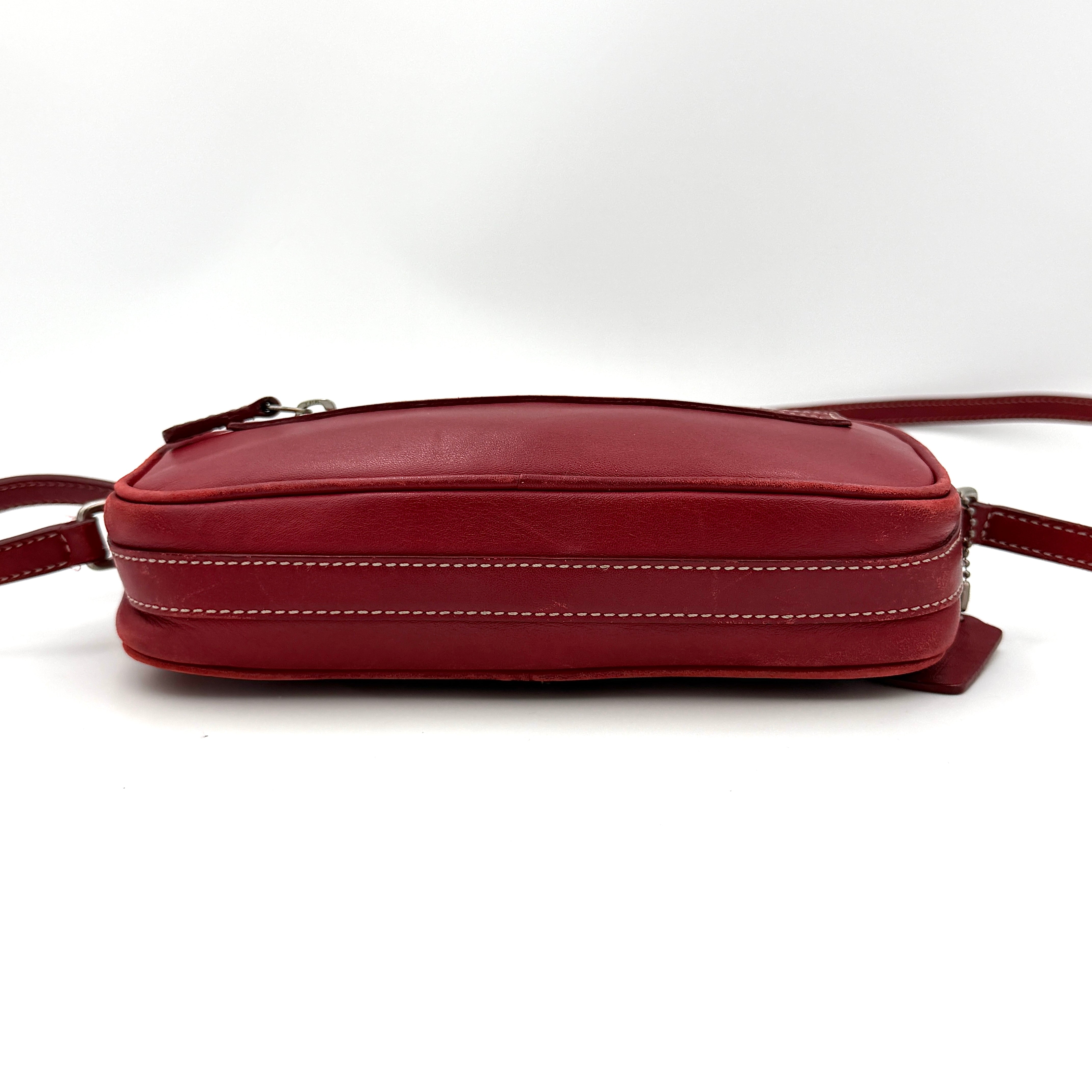 Burgundy Coach Legacy West Crossbody Camera Bag with contrast stitching, exterior zip pocket, and slender adjustable strap.