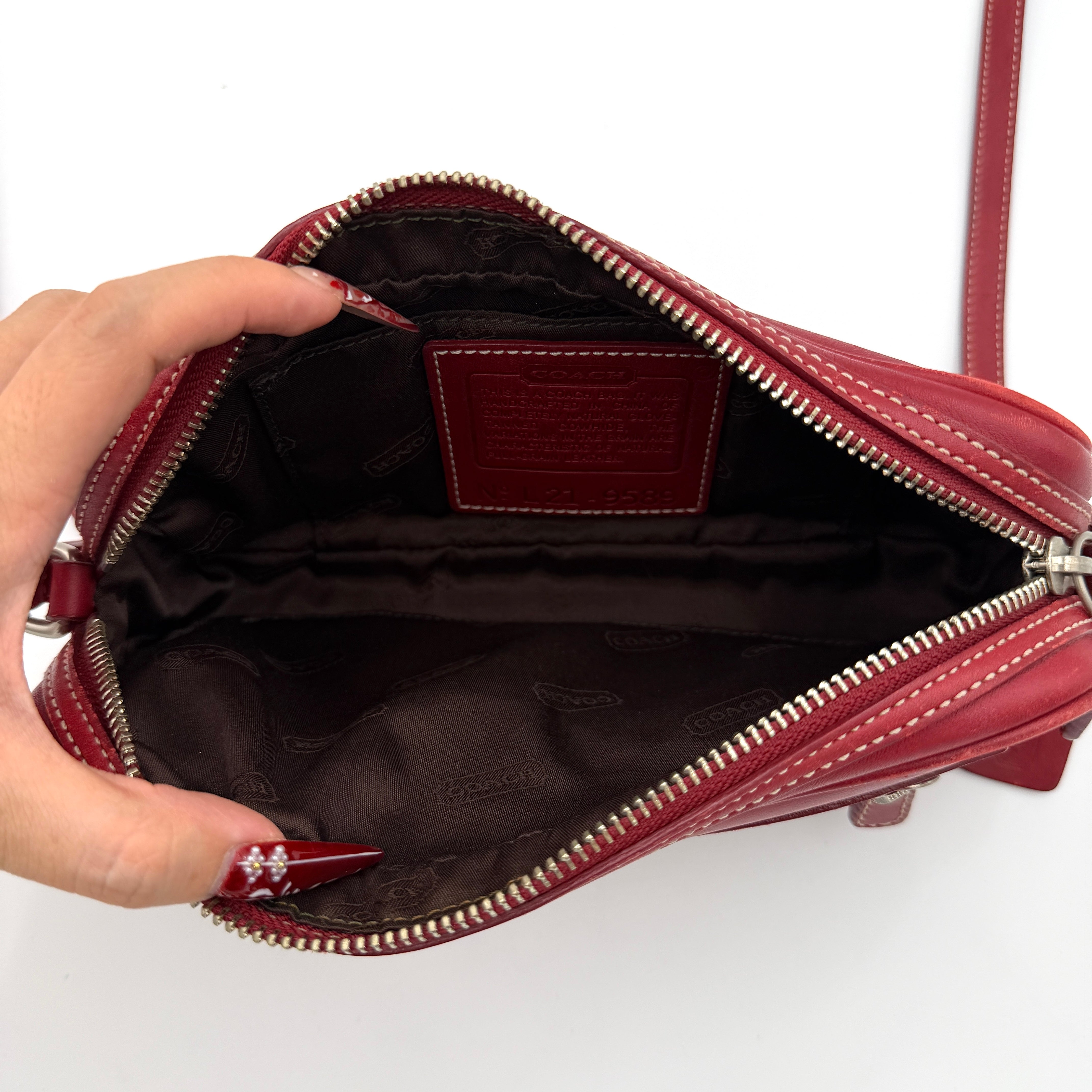 Burgundy Coach Legacy West Crossbody Camera Bag with contrast stitching, exterior zip pocket, and slender adjustable strap.