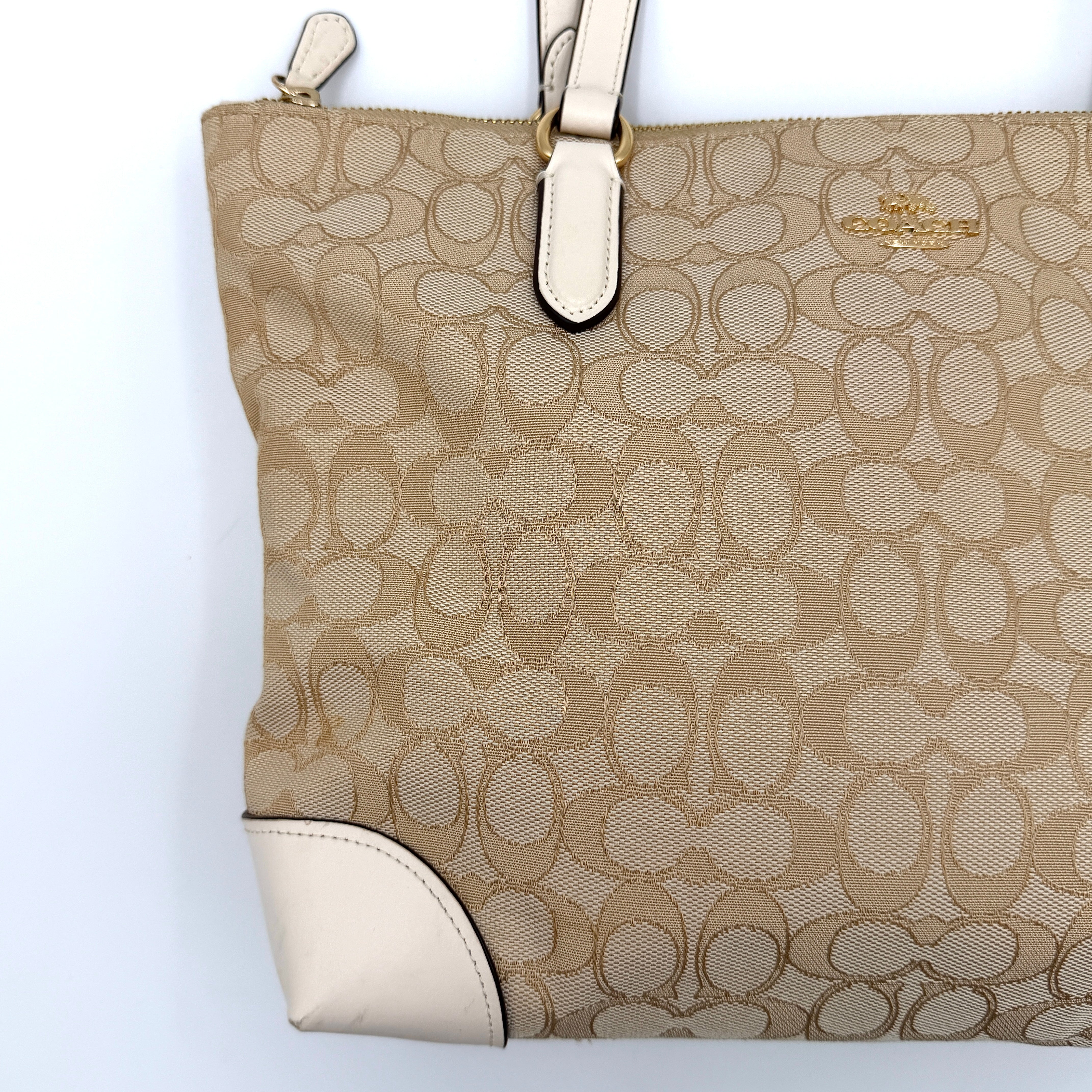 Coach Signature Zip Top Tote Bag in beige canvas with white leather trim and double handles, featuring the signature monogram print.