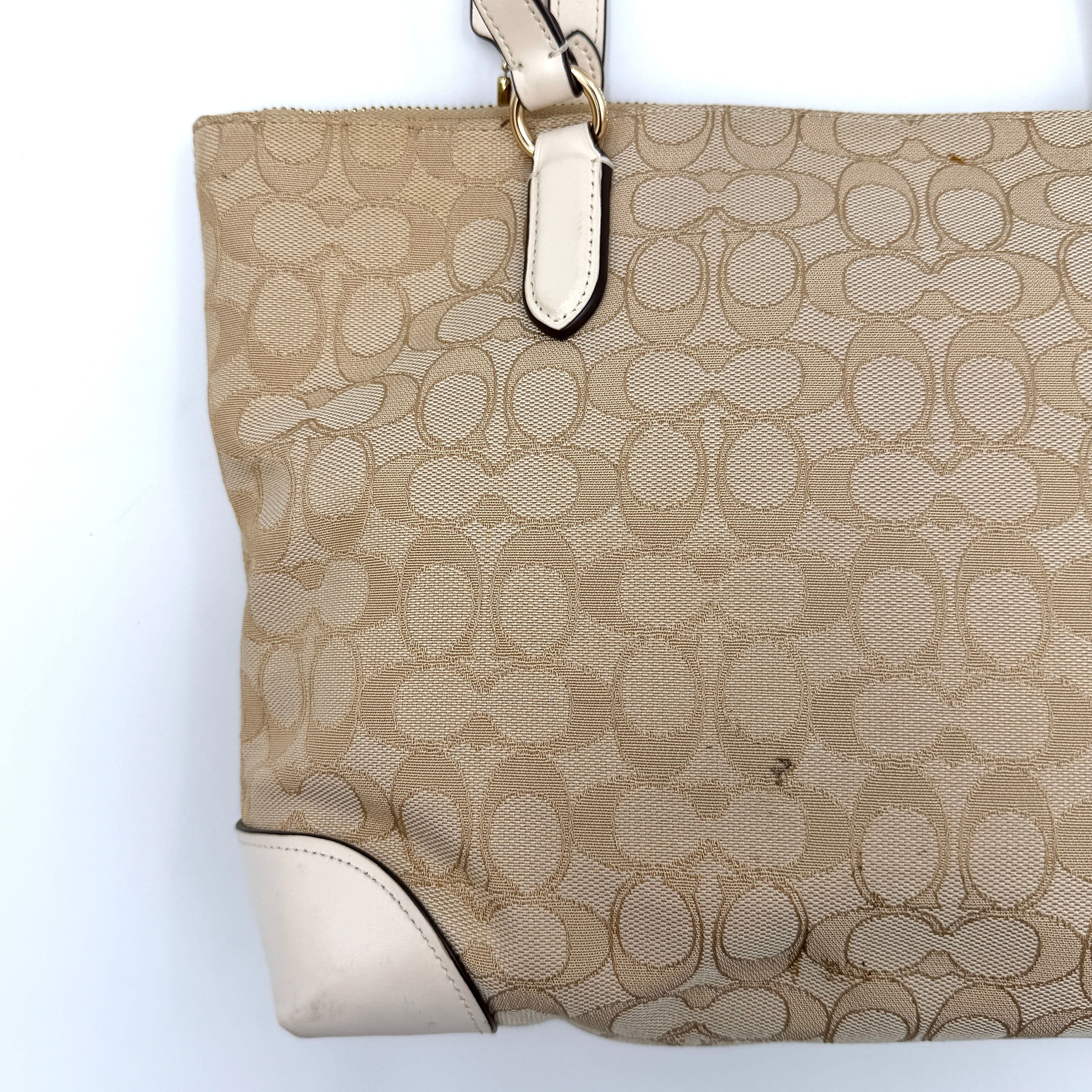 Coach Signature Zip Top Tote Bag in beige canvas with white leather trim and double handles, featuring the signature monogram print.