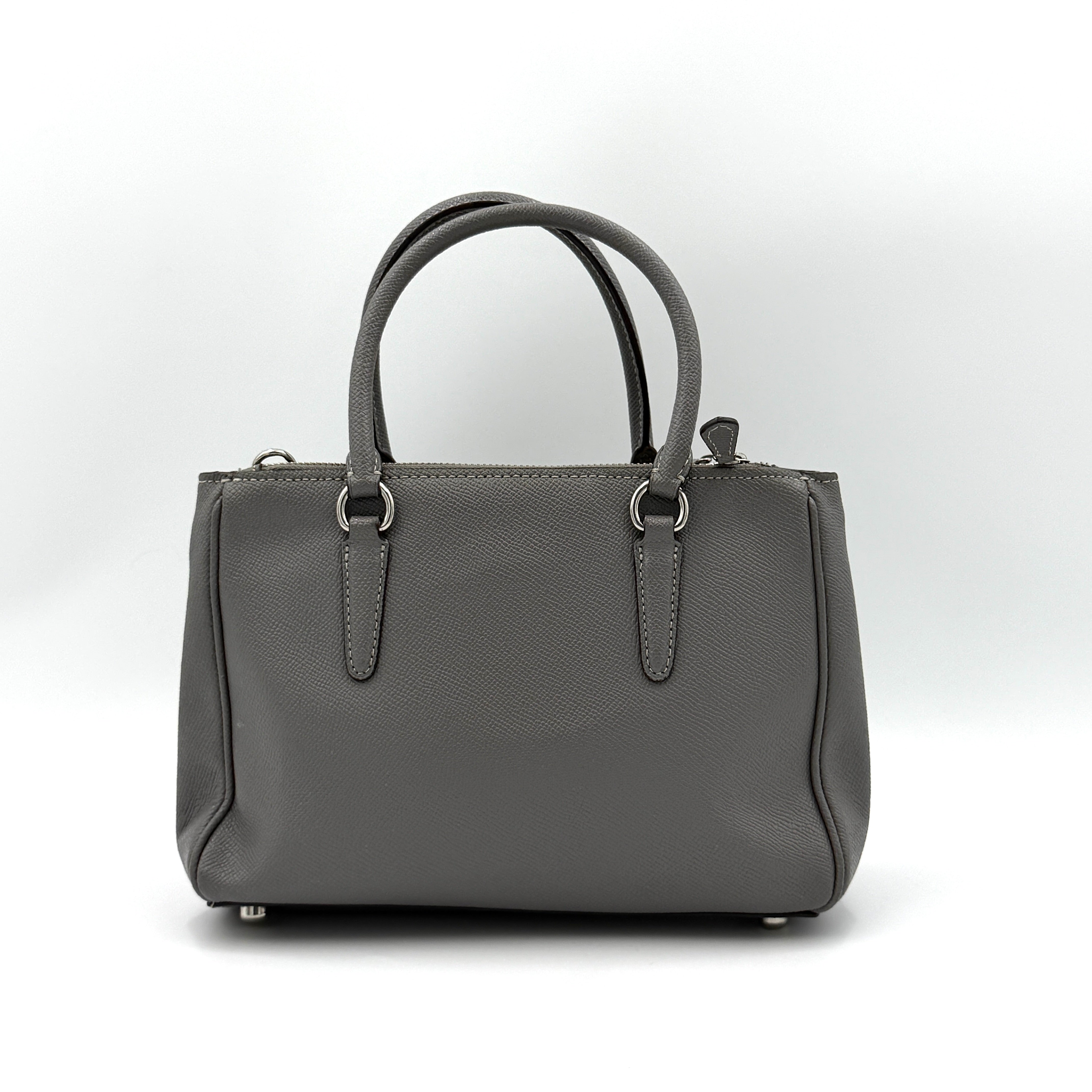 Coach 2Way Mini Surrey Carryall Handbag in grey textured leather with top handles and detachable strap, styled against a clean background.