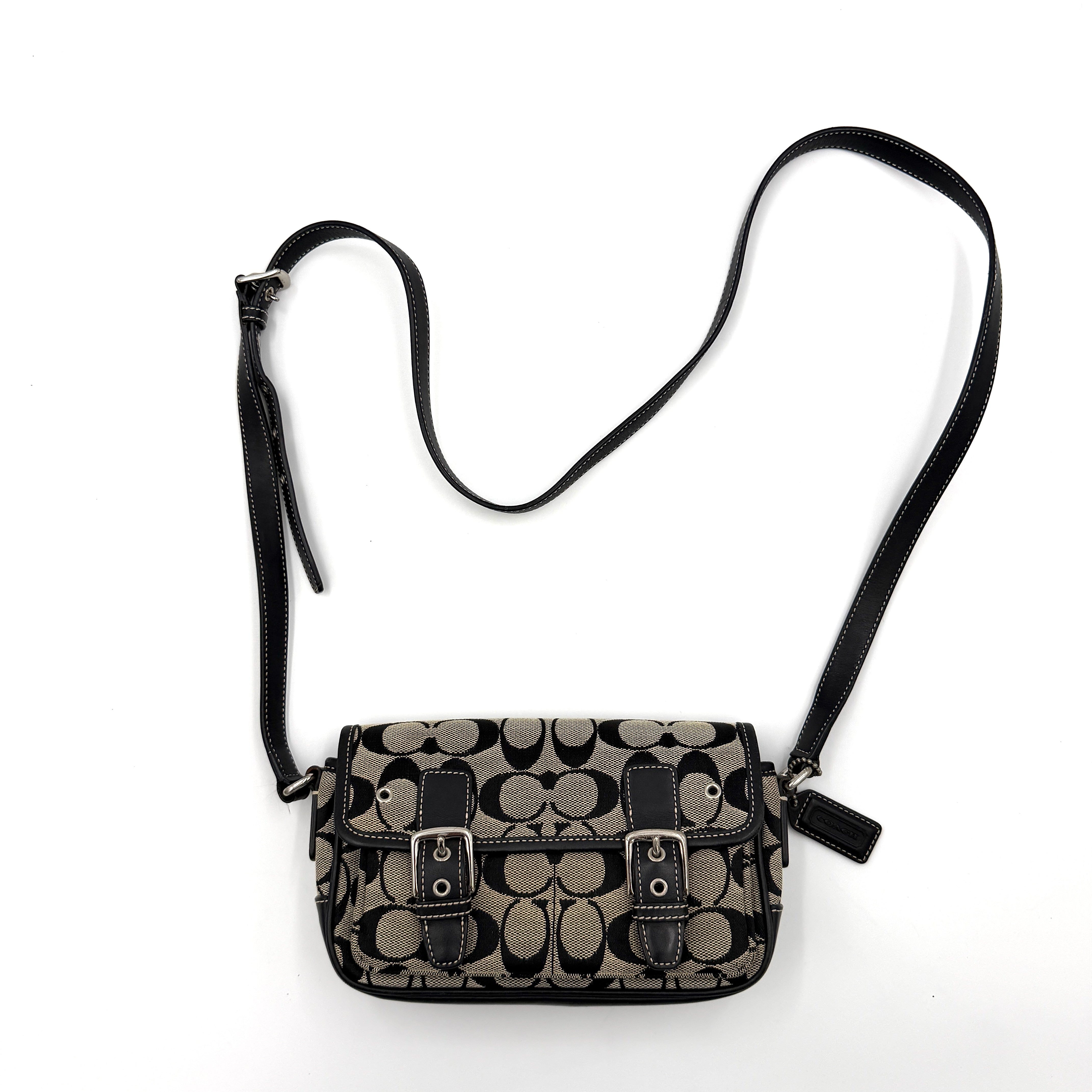 Coach Signature Double Buckle Crossbody bag in grey and black jacquard canvas, accented with black leather trim and dual silver-tone buckle detailing.