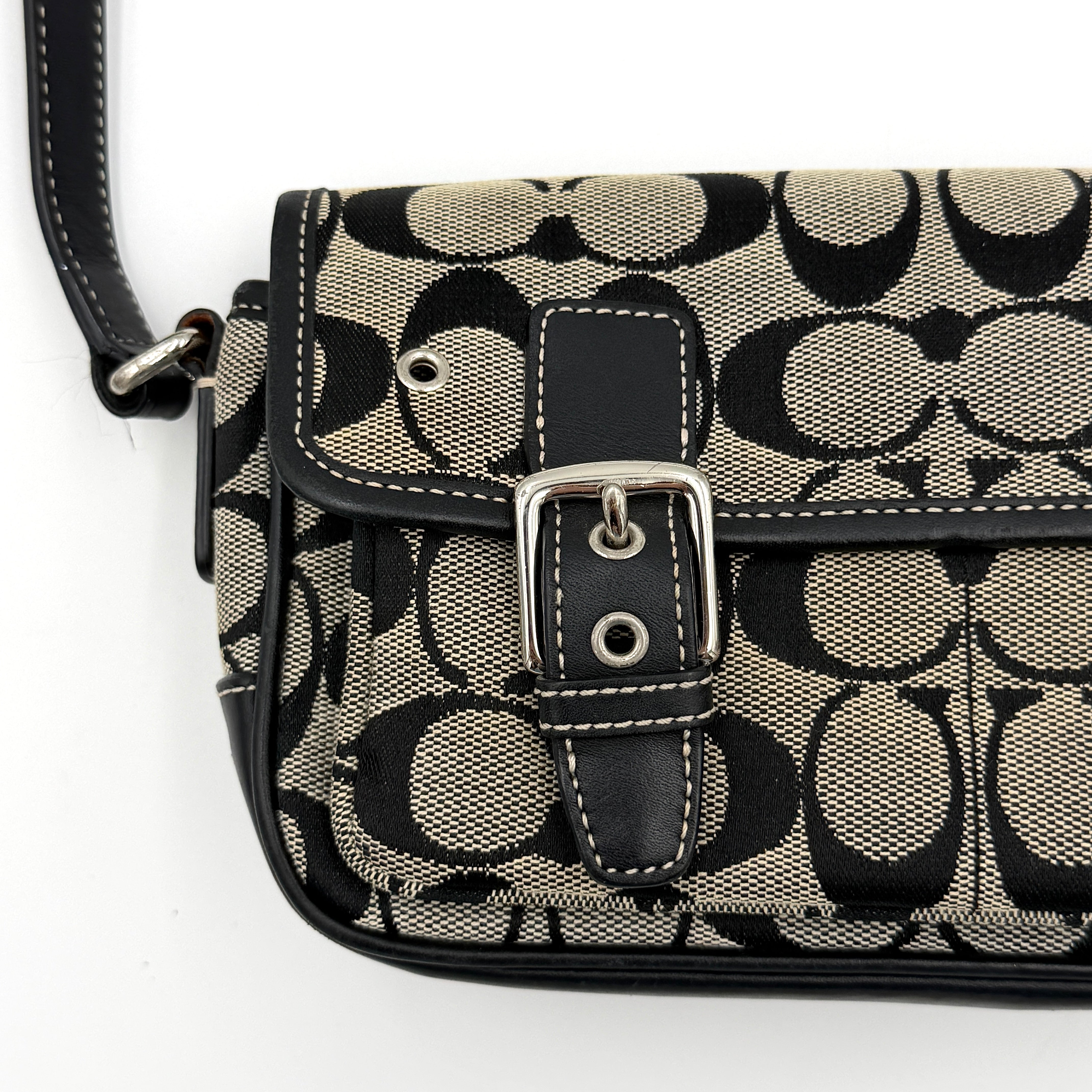 Coach Signature Double Buckle Crossbody bag in grey and black jacquard canvas, accented with black leather trim and dual silver-tone buckle detailing.