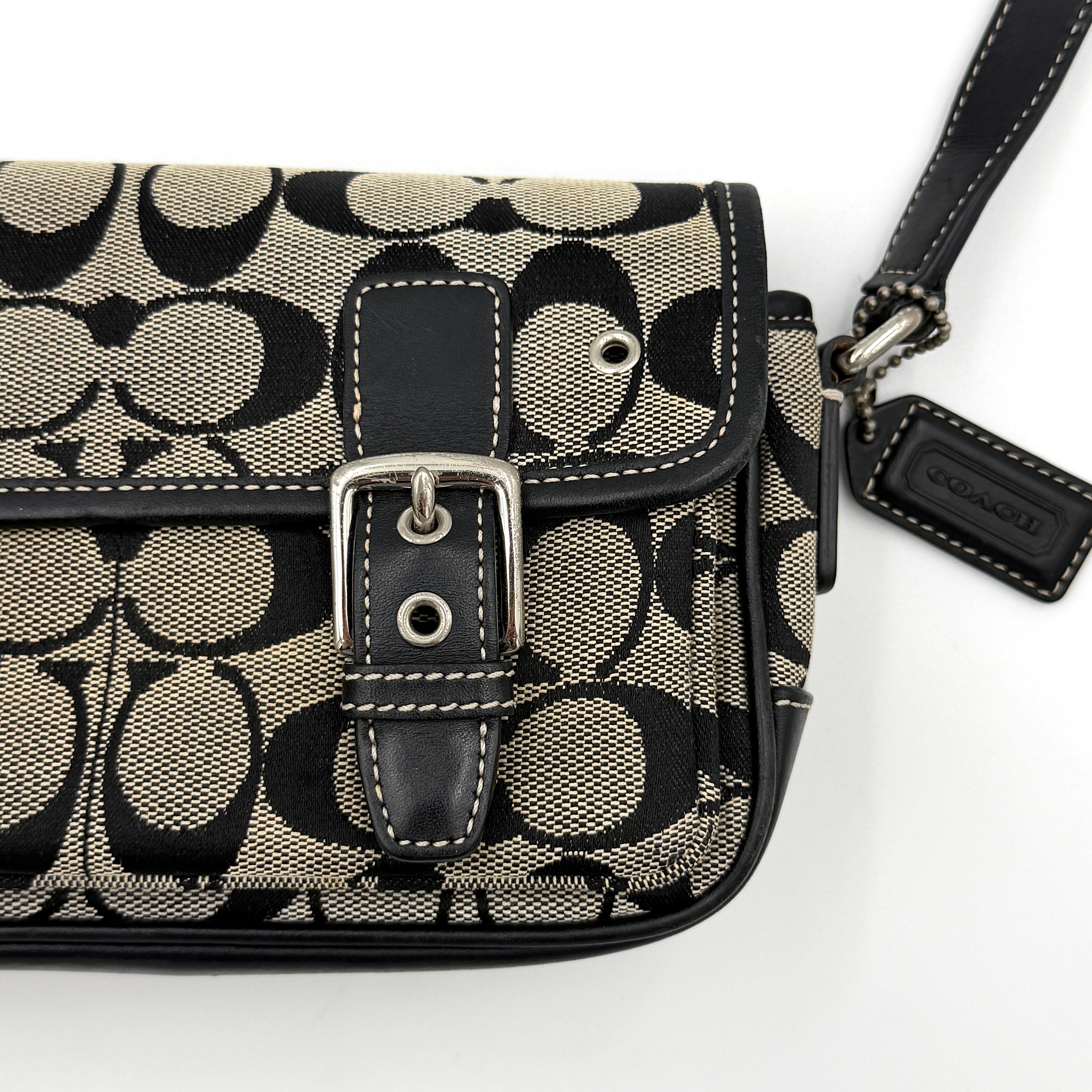 Coach Signature Double Buckle Crossbody bag in grey and black jacquard canvas, accented with black leather trim and dual silver-tone buckle detailing.