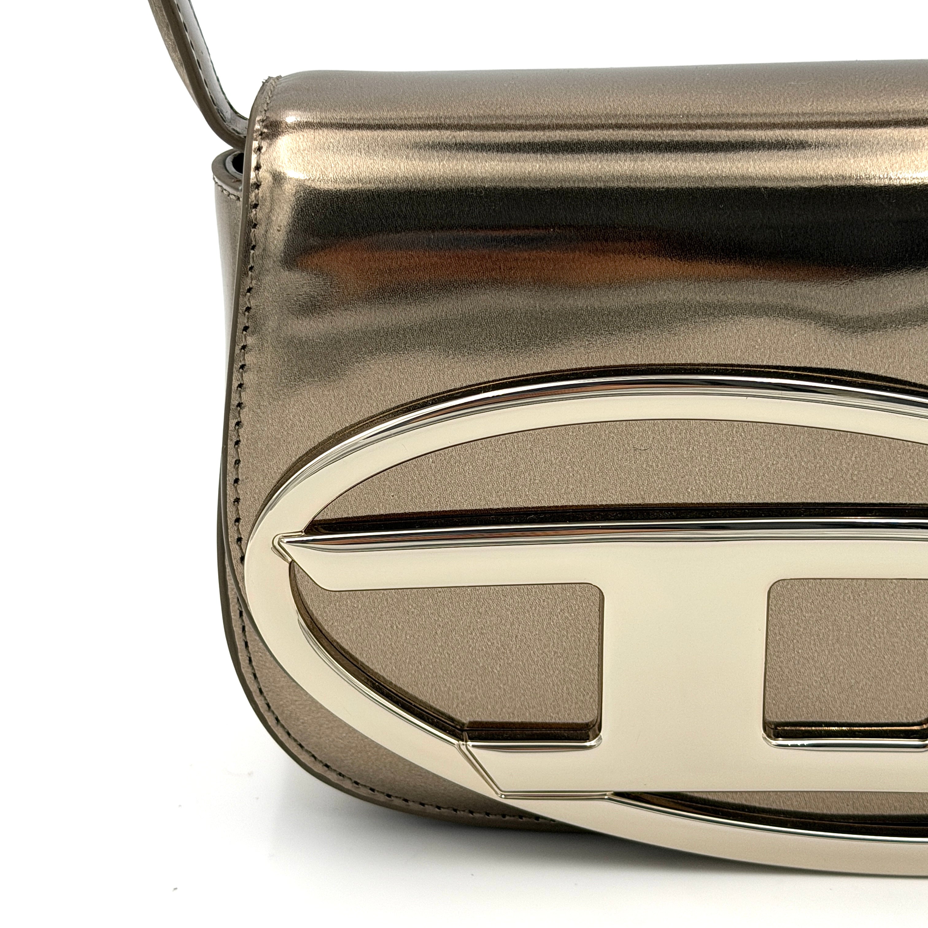 Diesel 1DR metallic silver shoulder bag with oversized chrome D-logo plaque, top handle, and detachable strap displayed against a white background.
