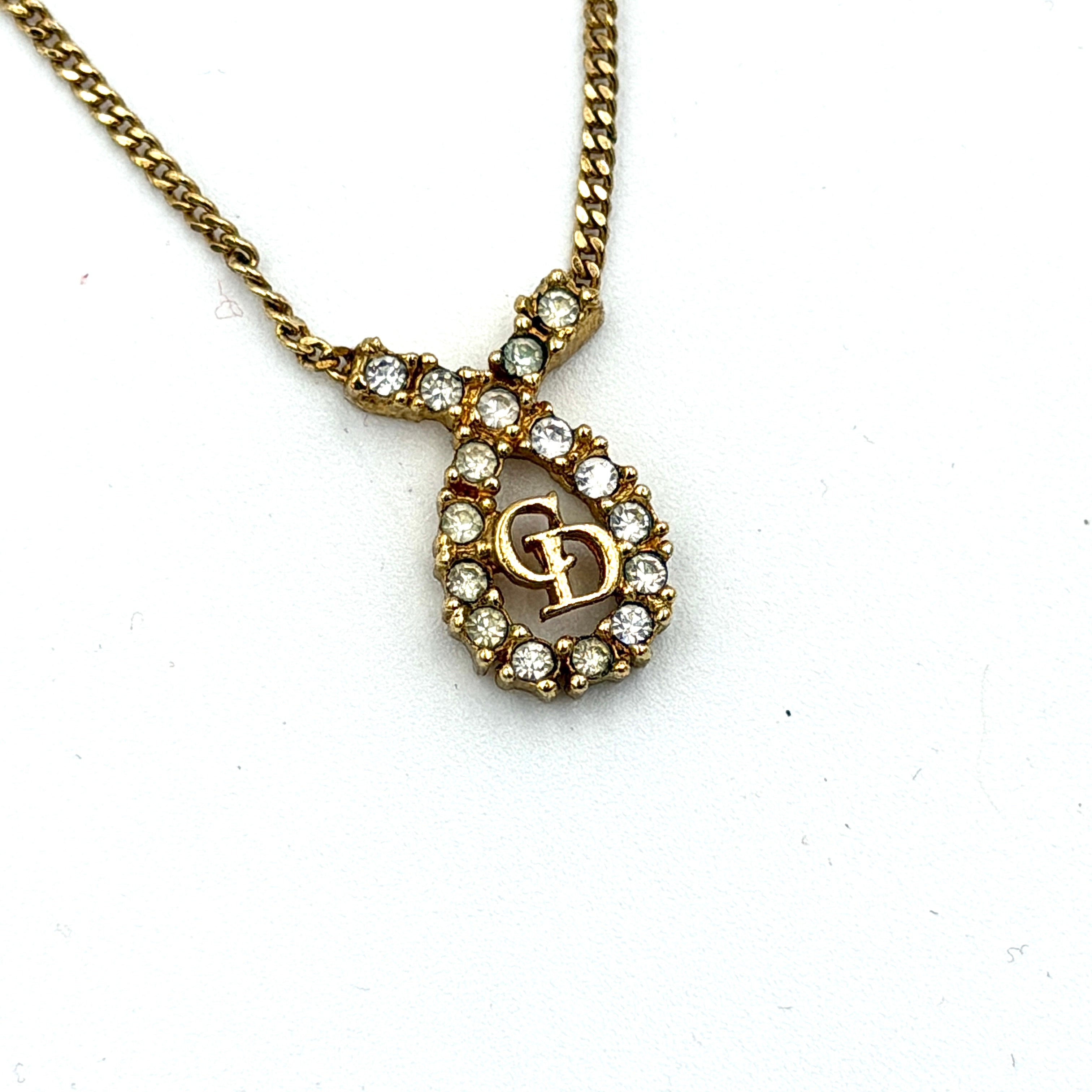 Dior CD Logo Rhinestone Necklace in gold featuring a teardrop pendant adorned with clear rhinestones and a gold chain.