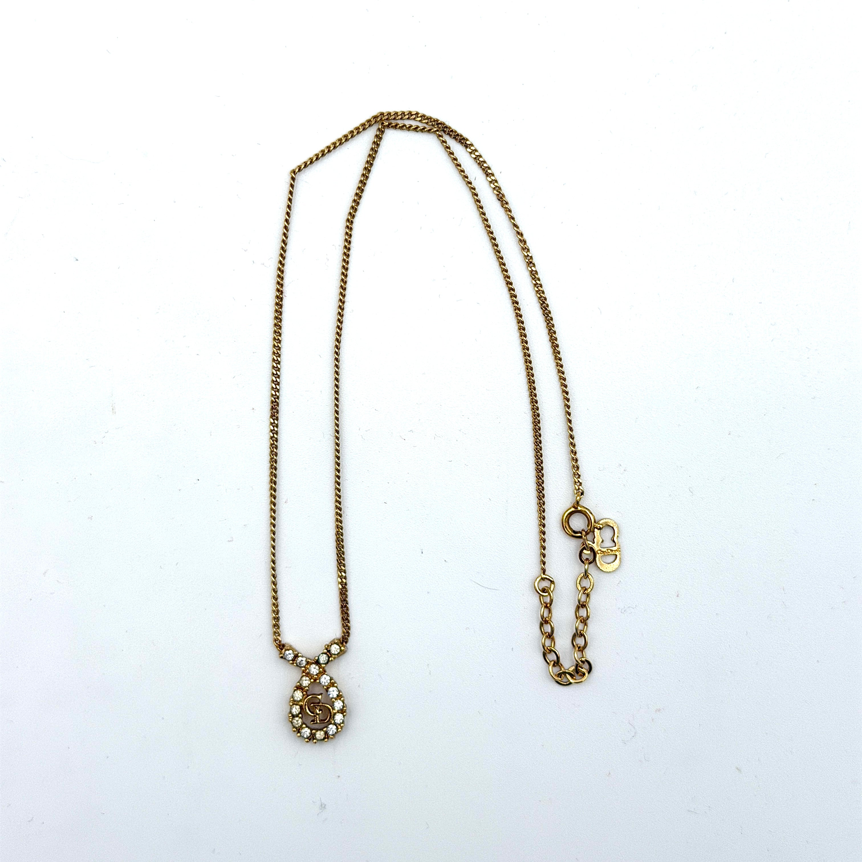 Dior CD Logo Rhinestone Necklace in gold featuring a teardrop pendant adorned with clear rhinestones and a gold chain.