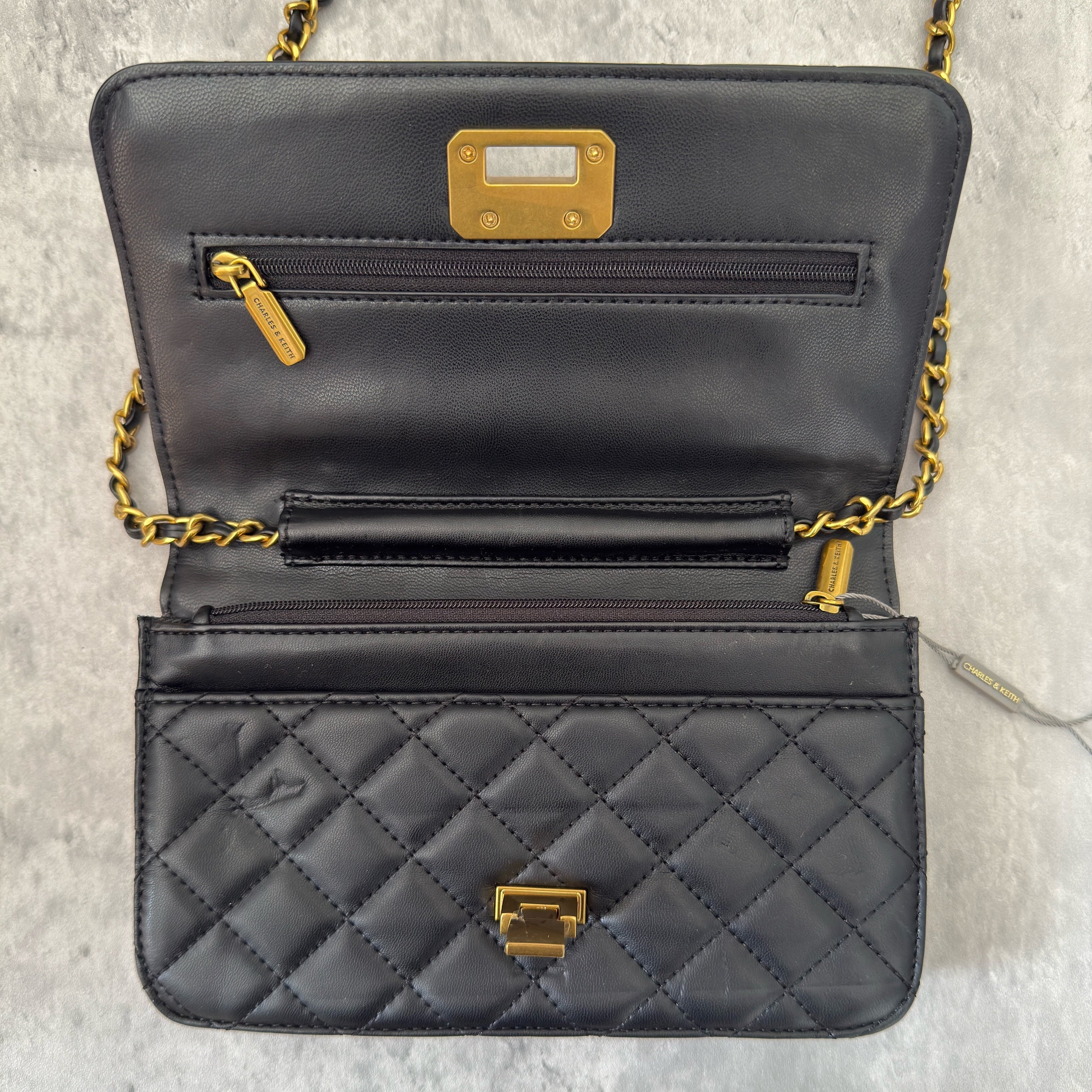 Charles & Keith Cressida Quilted Push-Lock Clutch Bag in black faux leather with gold-tone chain strap and secure push-lock closure.