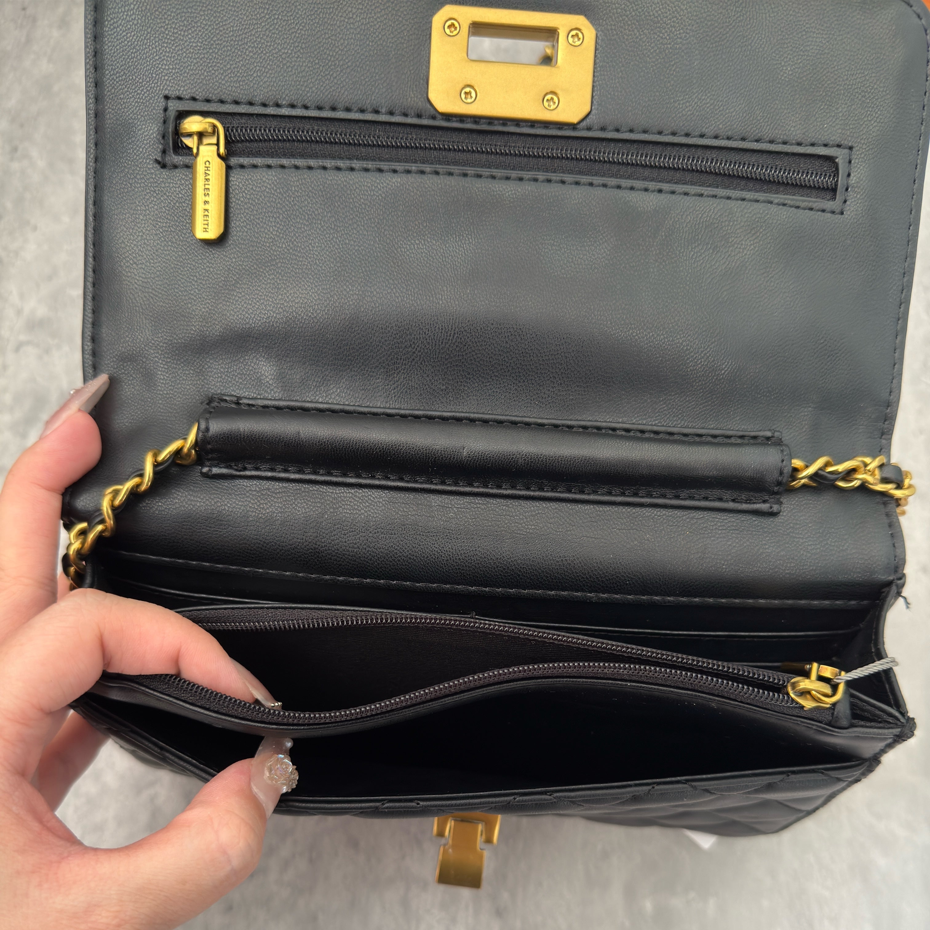 Charles & Keith Cressida Quilted Push-Lock Clutch Bag in black faux leather with gold-tone chain strap and secure push-lock closure.