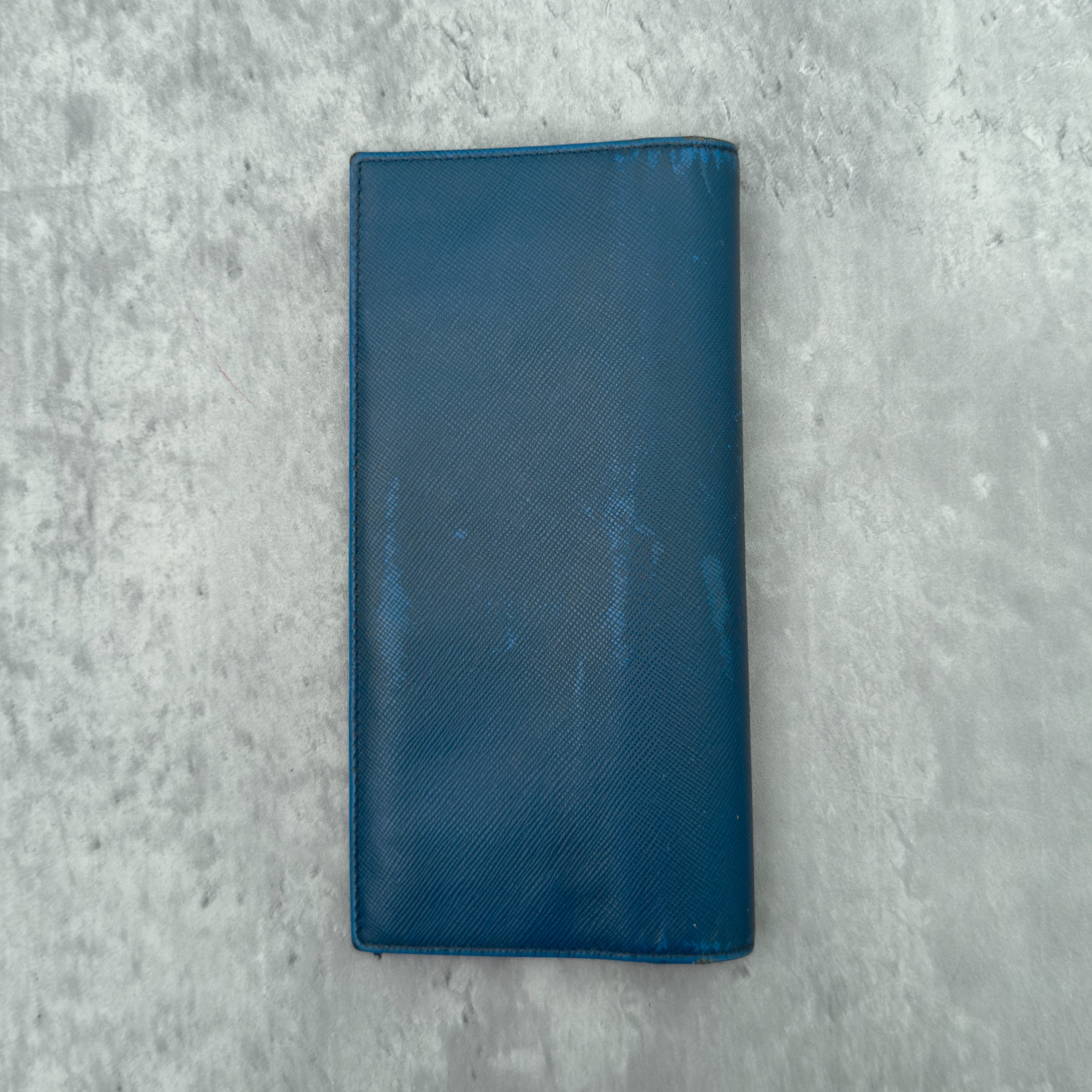 Prada Saffiano Baby Blue Long Wallet in Saffiano leather, featuring an embossed Prada logo, multiple card slots, and a zippered coin compartment.