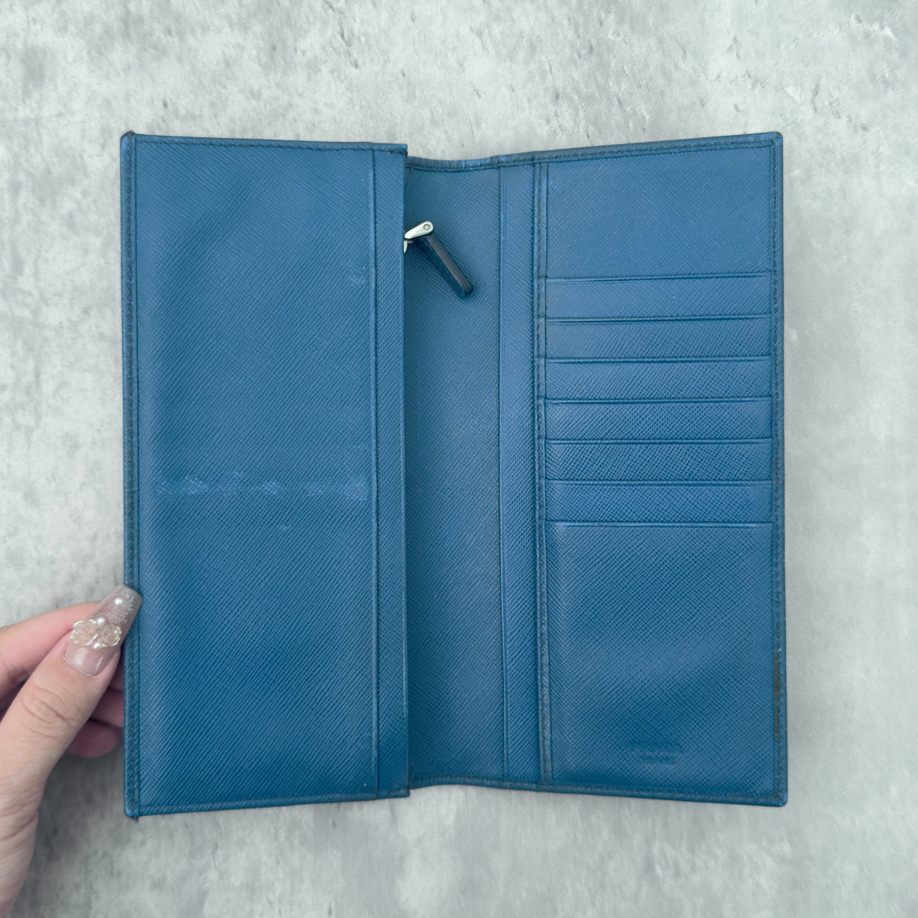 Prada Saffiano Baby Blue Long Wallet in Saffiano leather, featuring an embossed Prada logo, multiple card slots, and a zippered coin compartment.
