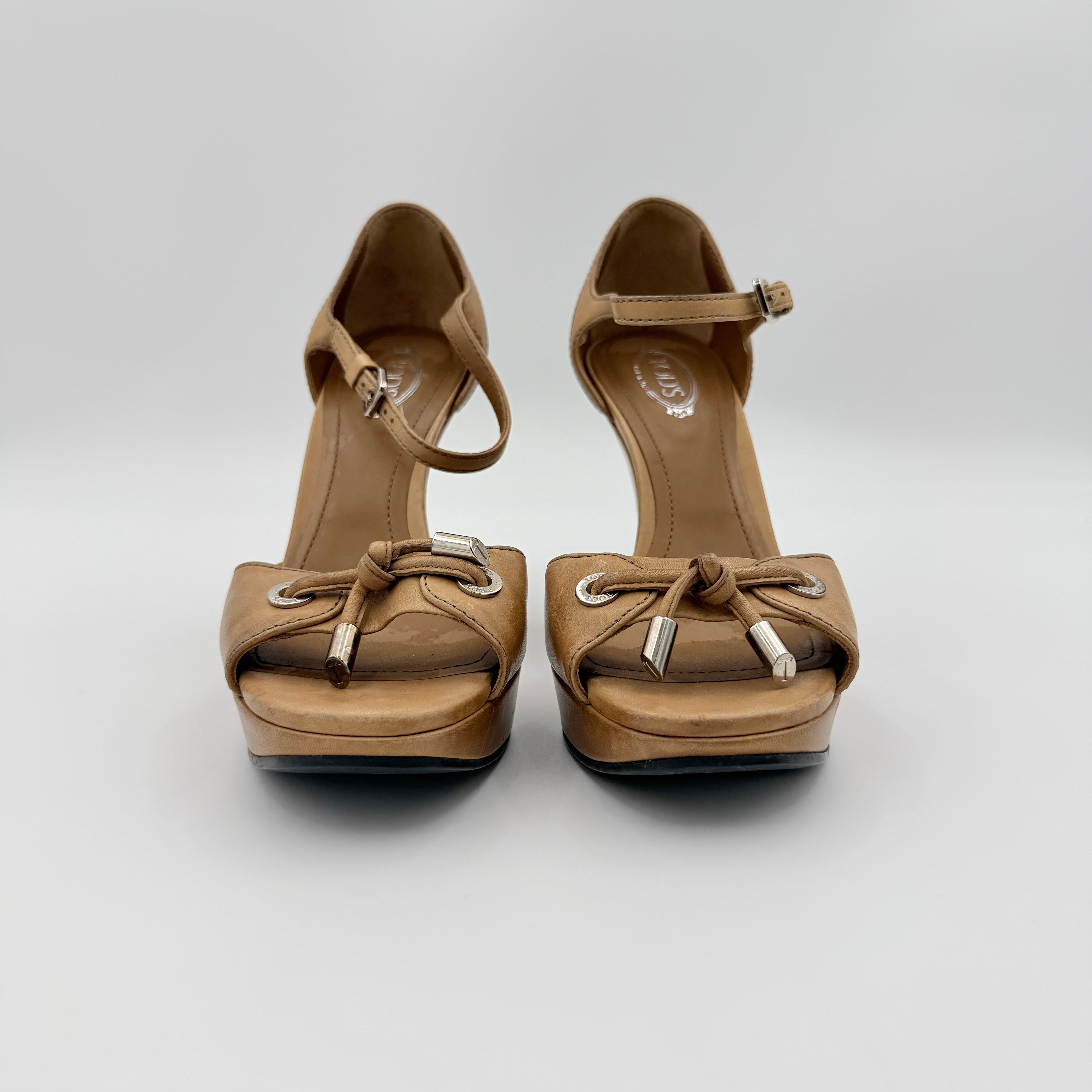 Tan leather Tod's peep-toe platform wedge sandals with ankle strap and front bow detail, shown from an angle.