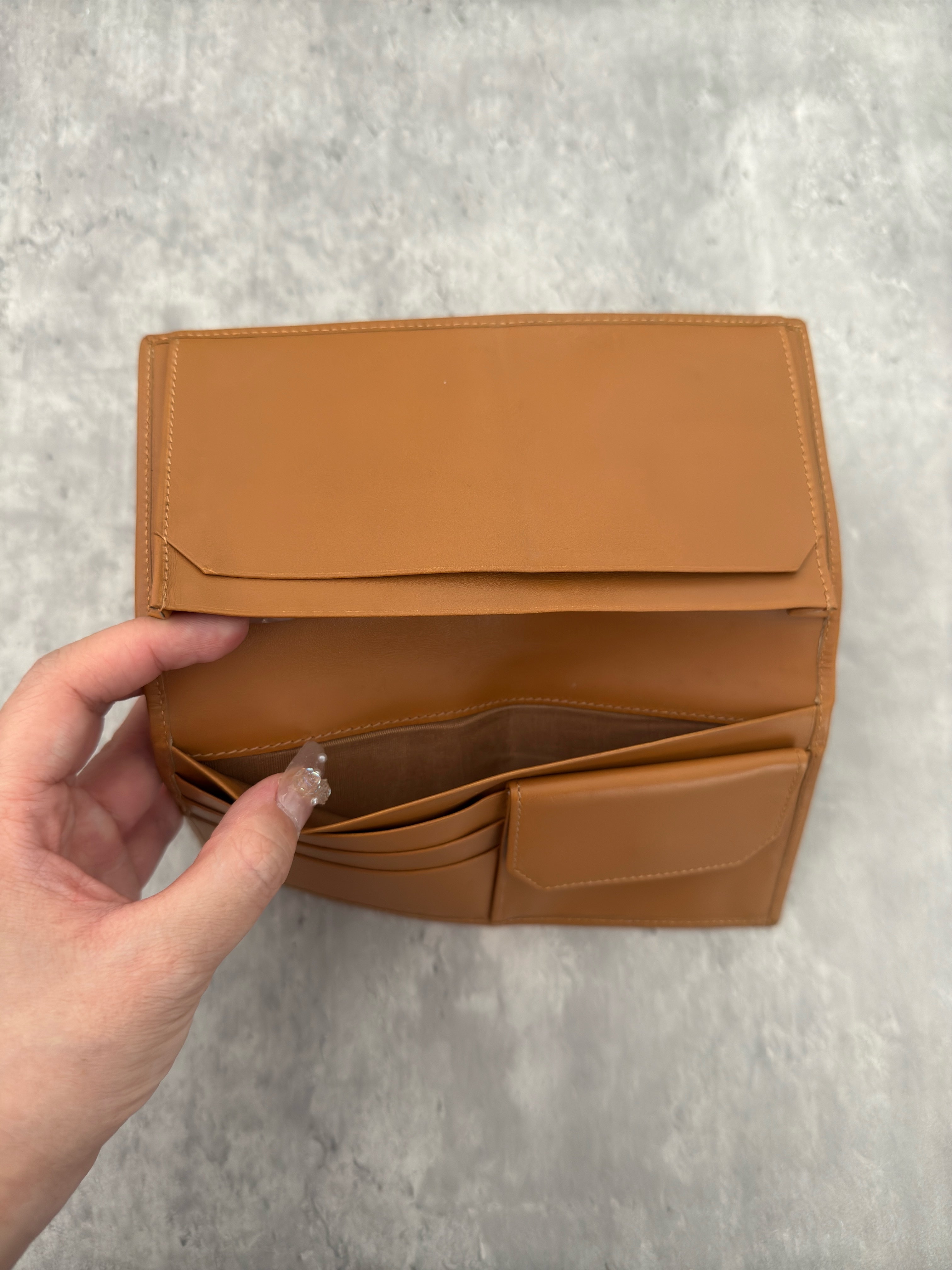 Celine Macadam Triomphe Canvas Long Wallet in brown monogram canvas with tan leather trim, featuring a bifold design with multiple compartments and a snap-button coin pocket.