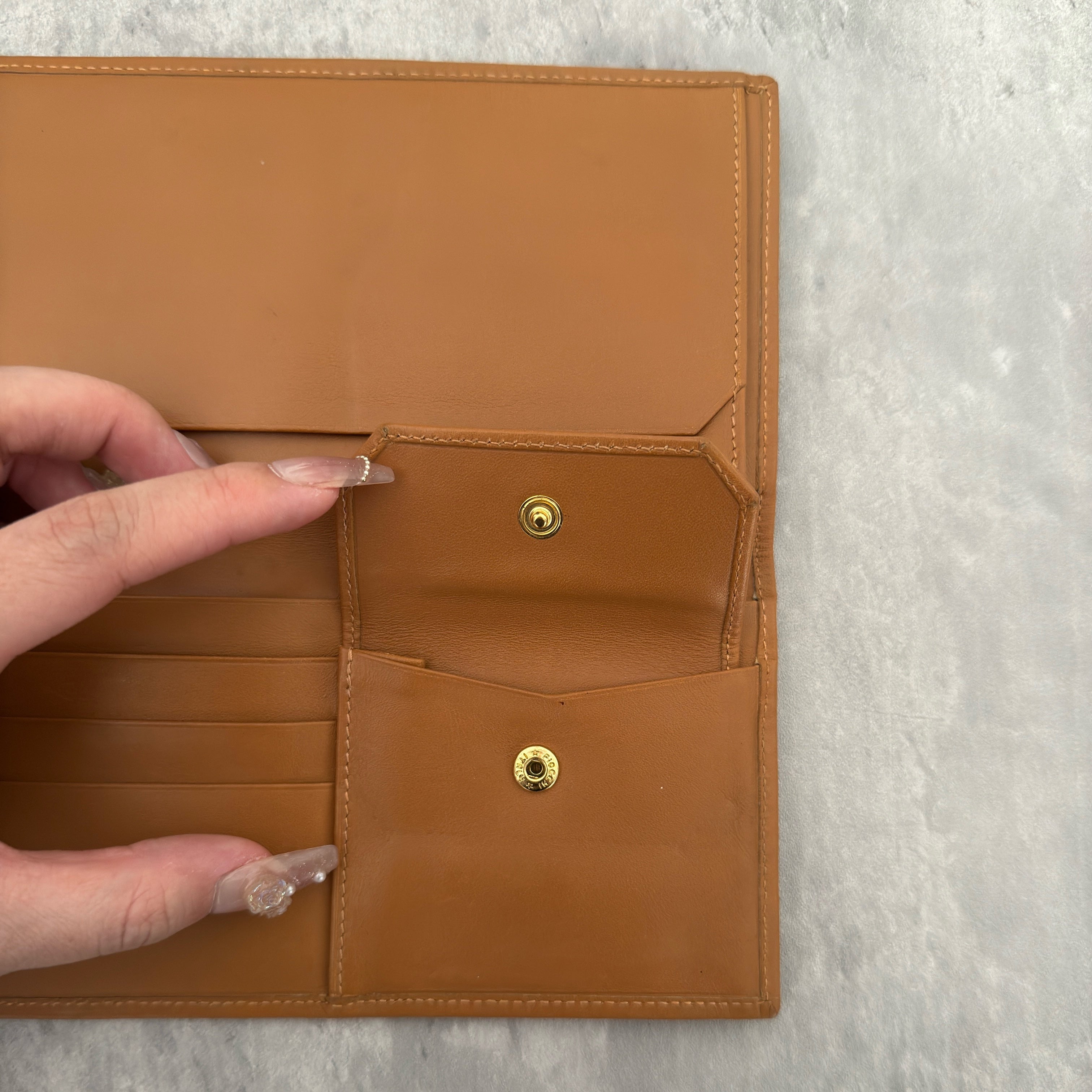 Celine Macadam Triomphe Canvas Long Wallet in brown monogram canvas with tan leather trim, featuring a bifold design with multiple compartments and a snap-button coin pocket.