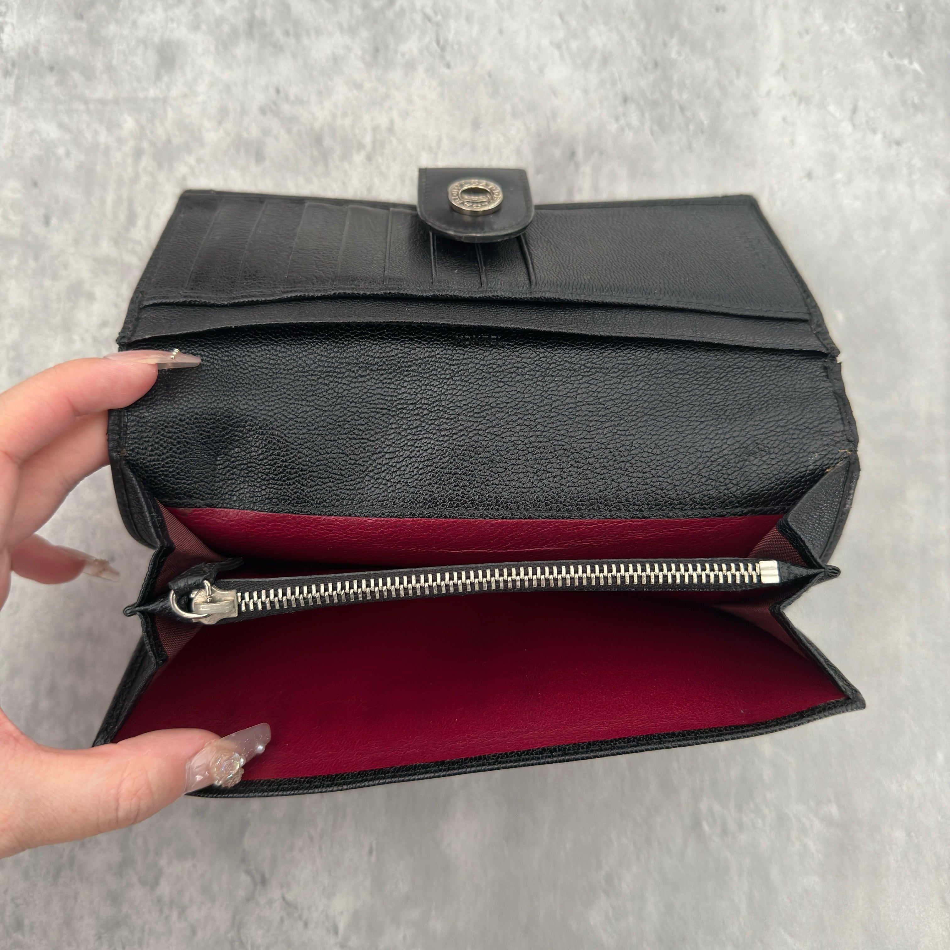 Bvlgari Doppio Tondo Bifold Long Wallet in black leather, featuring a silver-tone logo clasp, red fabric interior, and multiple compartments.