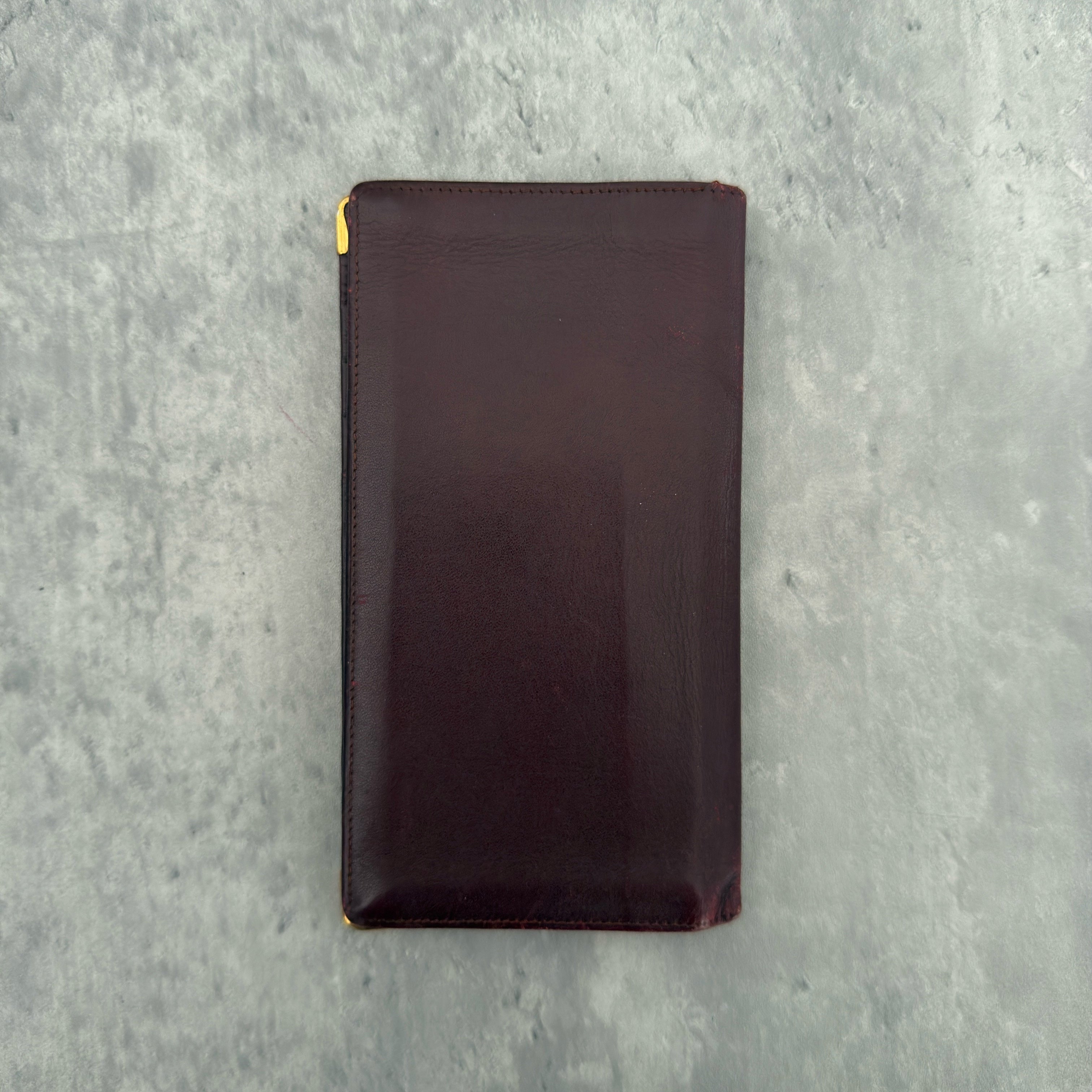 Cartier Must De Cartier Burgundy Long Wallet in burgundy leather with gold-tone corner accents and multiple compartments.