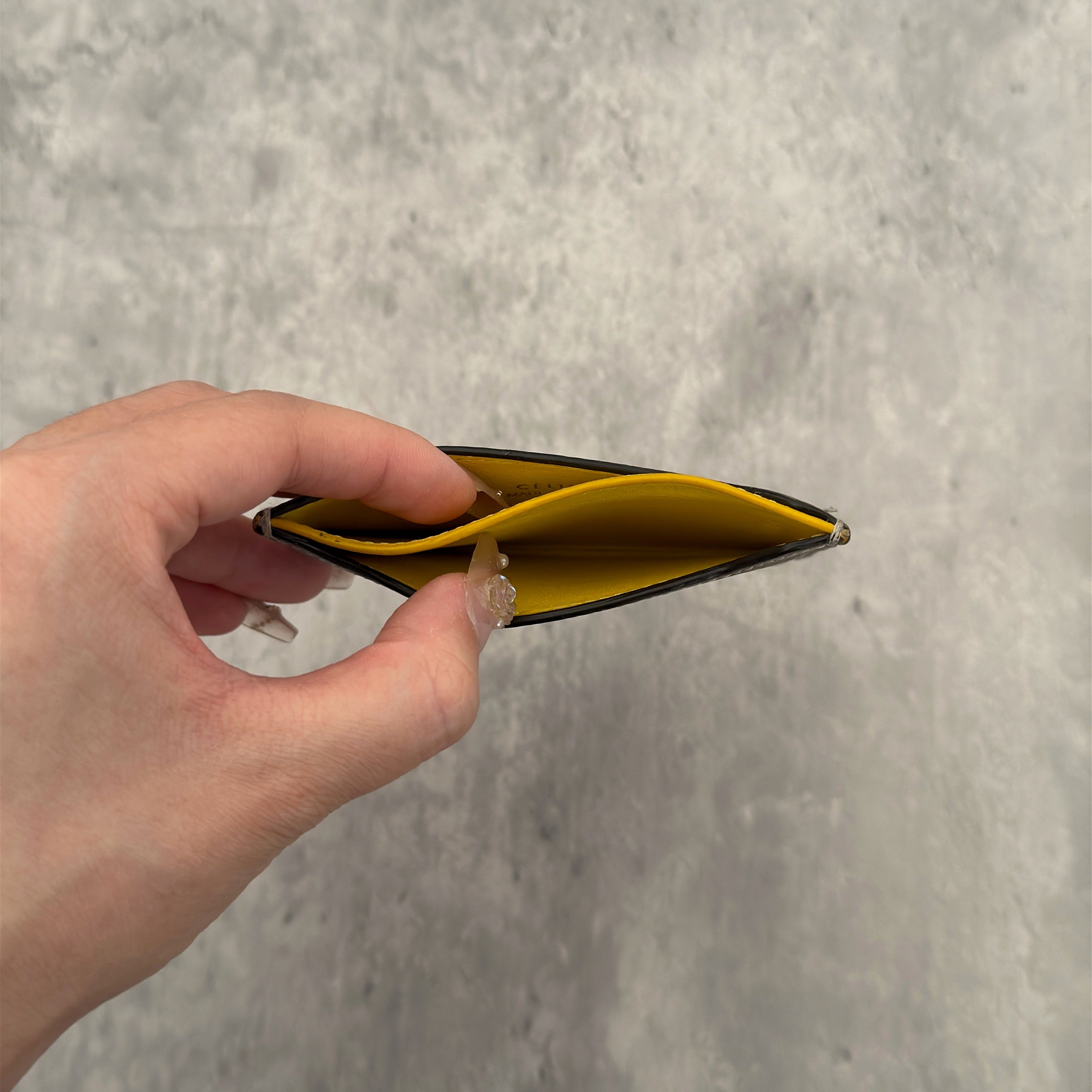 Celine Drummed Calfskin Bi-Color Cardholder in olive green and yellow, featuring a minimalist design with multiple card slots and central pocket.