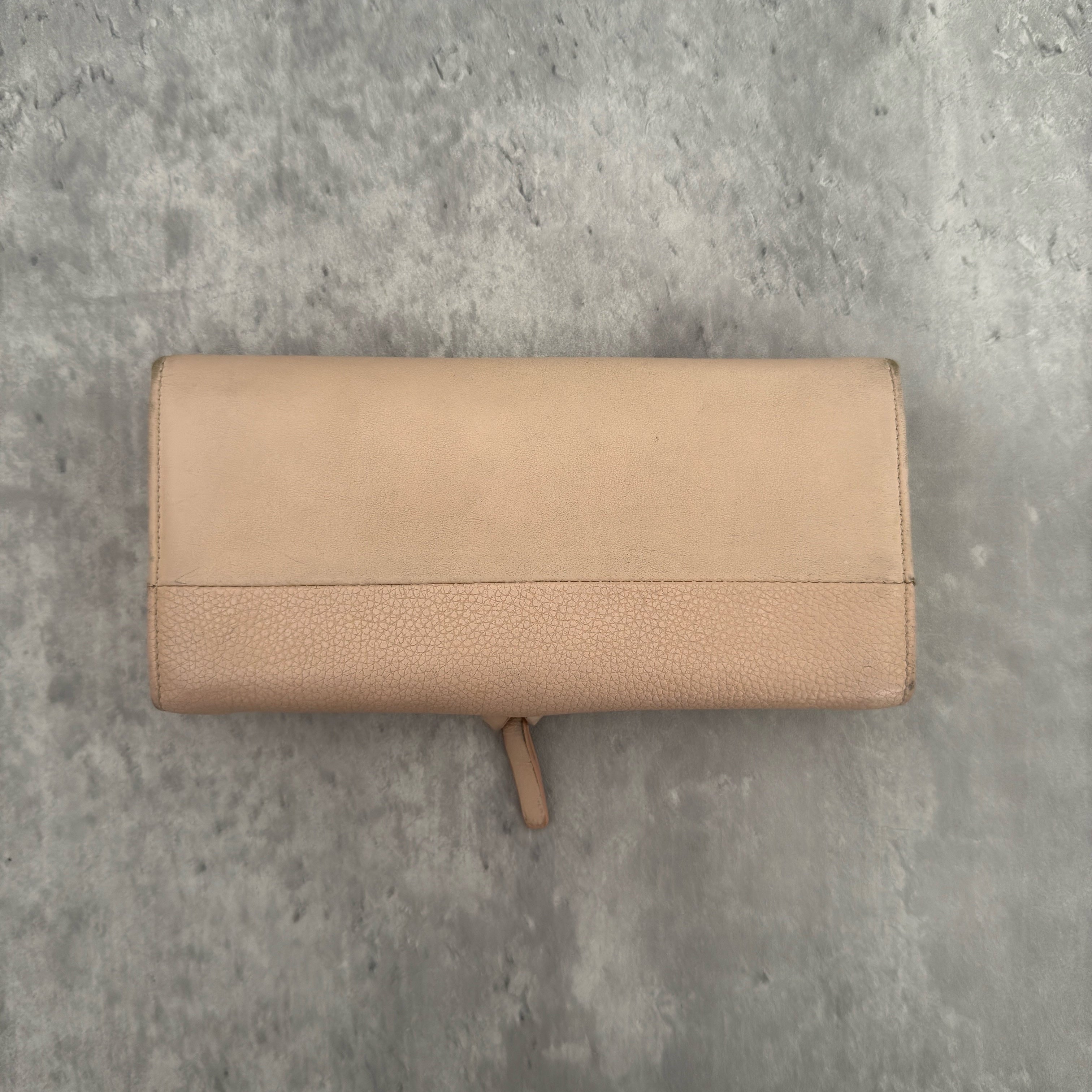 Chloe Grained Smooth Calfskin Indy Long Wallet in Light Pink, featuring a gold-tone circular medallion closure with leather tie detail, crafted from a mix of grained and smooth calfskin leather.