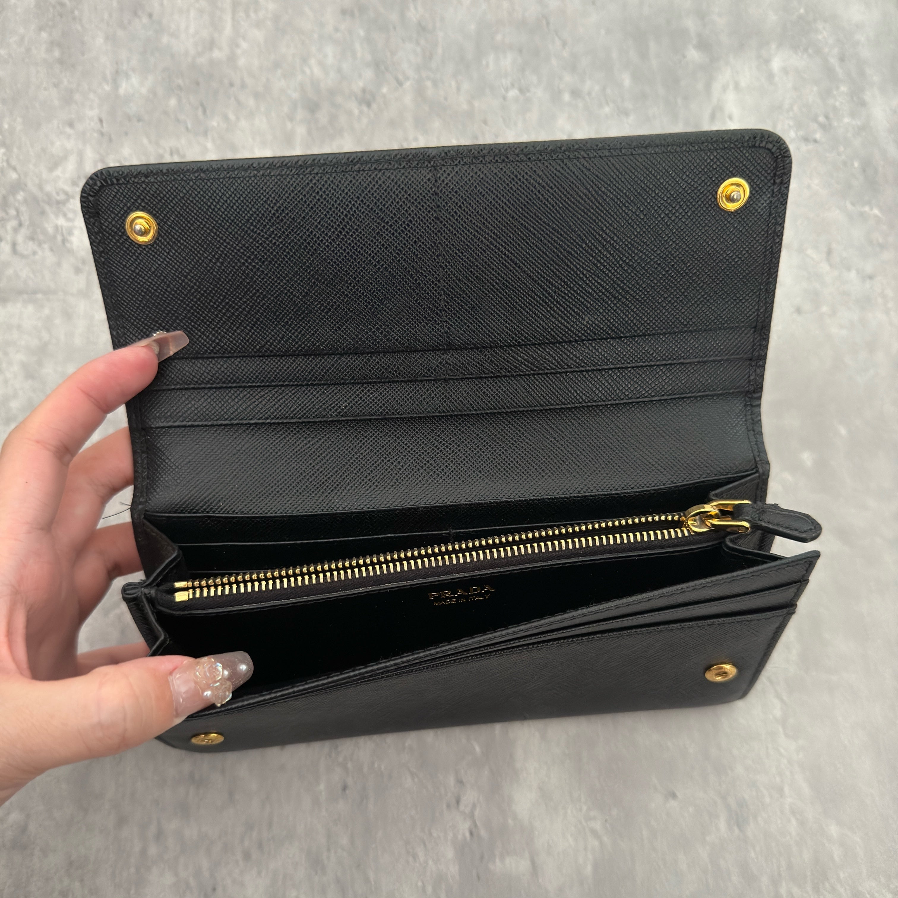 Prada Milano Black Saffiano Leather Ribbon Bow Long Wallet, crafted from textured black Saffiano leather with a gold-tone logo plaque and ribbon bow detail.