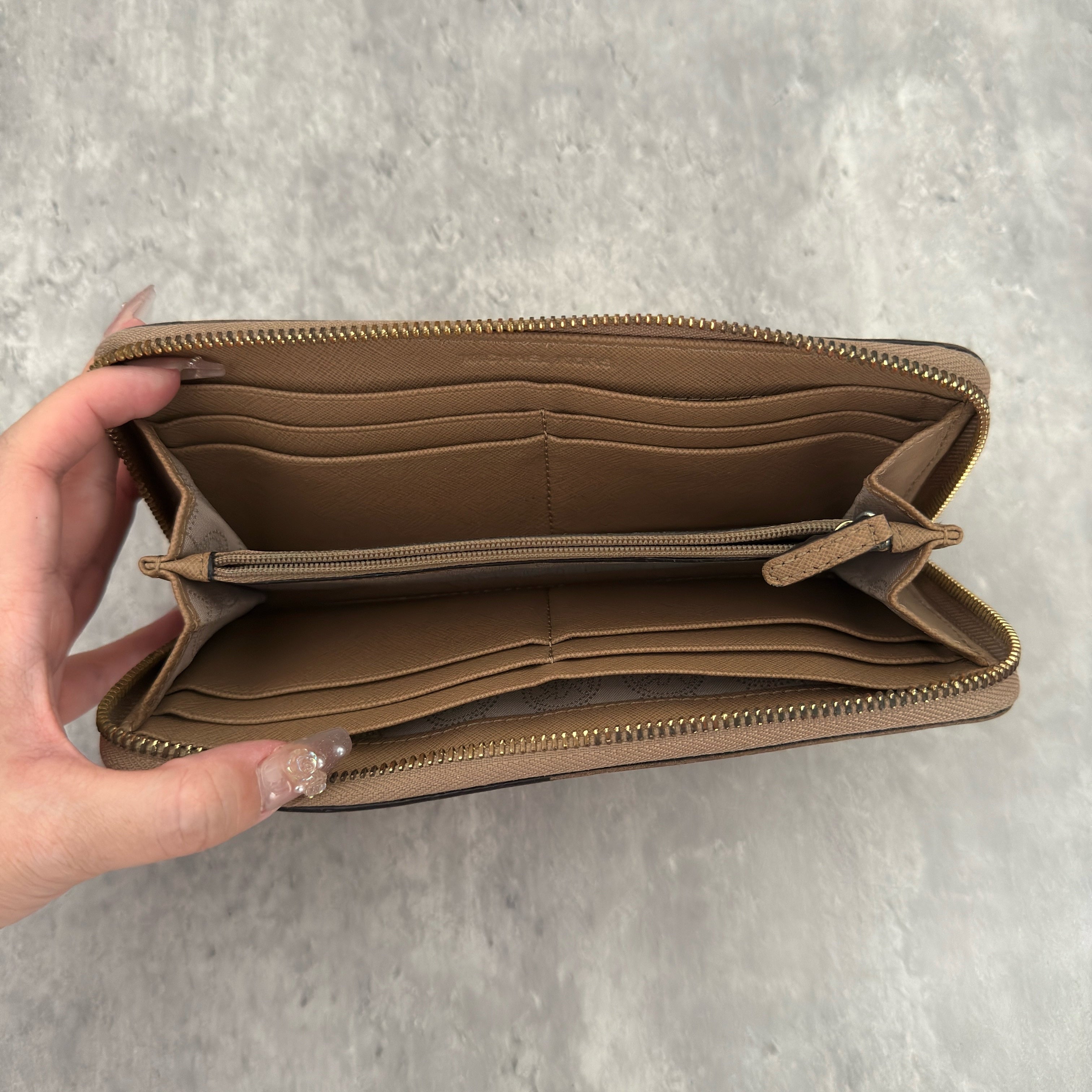 Michael Kors Jet Set Travel Zip-Around Saffiano Leather Continental Wallet in brown, featuring a gold-tone MK logo and zip-around closure.