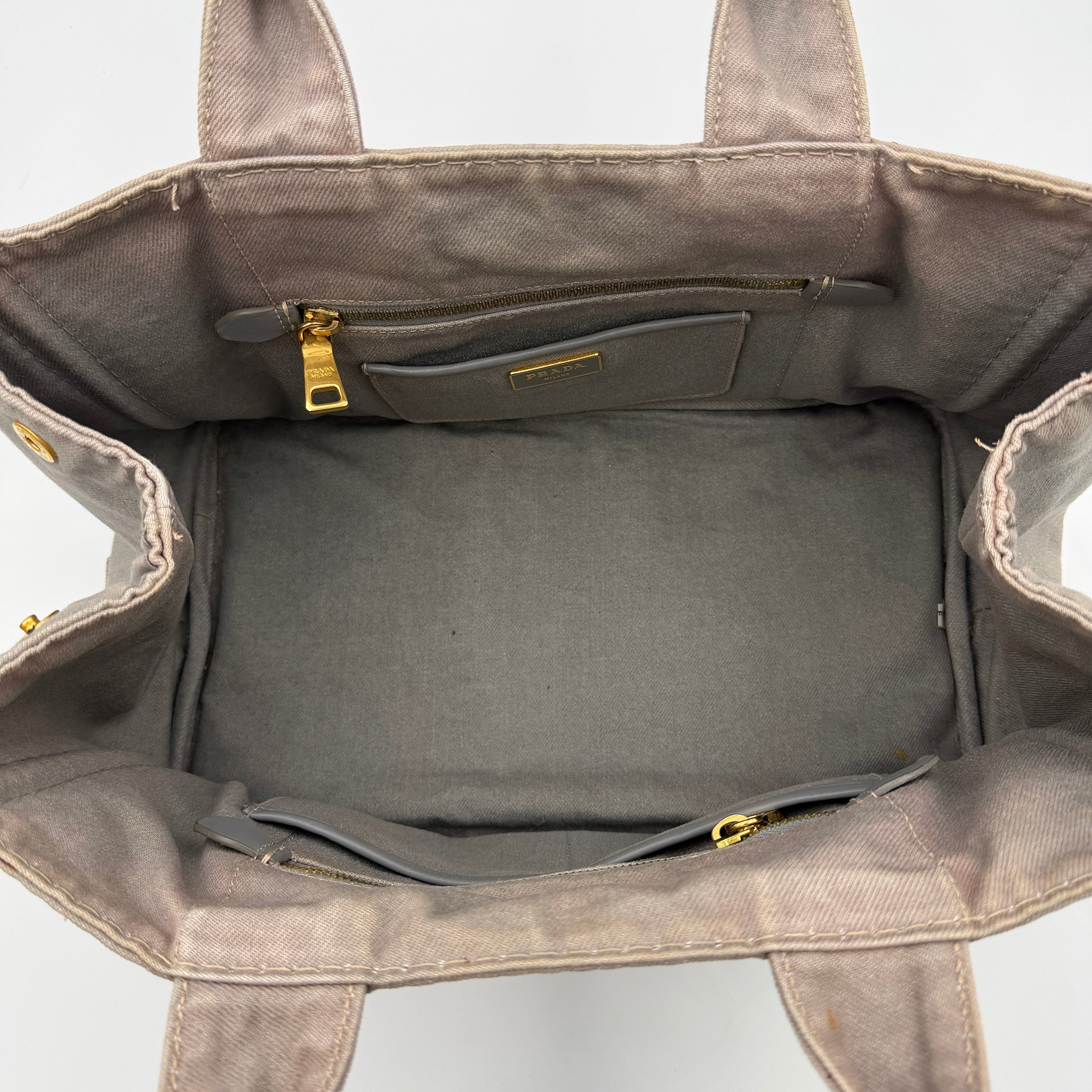Prada Canapa Tote Bag in grey canvas with rope logo motif and dual top handles against a plain background.
