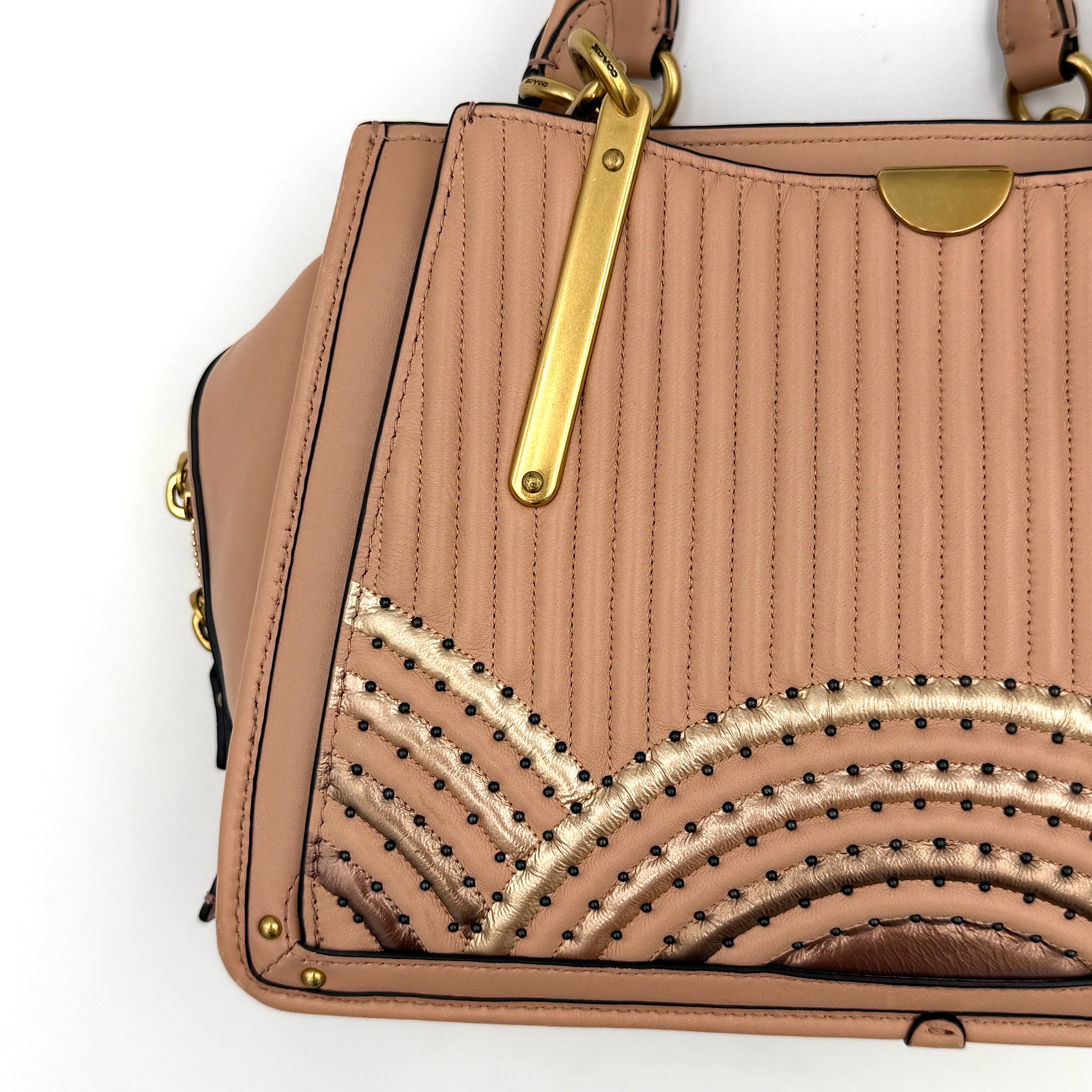 Coach Dreamer 27 handbag in nude pink leather with Deco quilting, gold rivets, and detachable strap, displayed elegantly on a plain background.