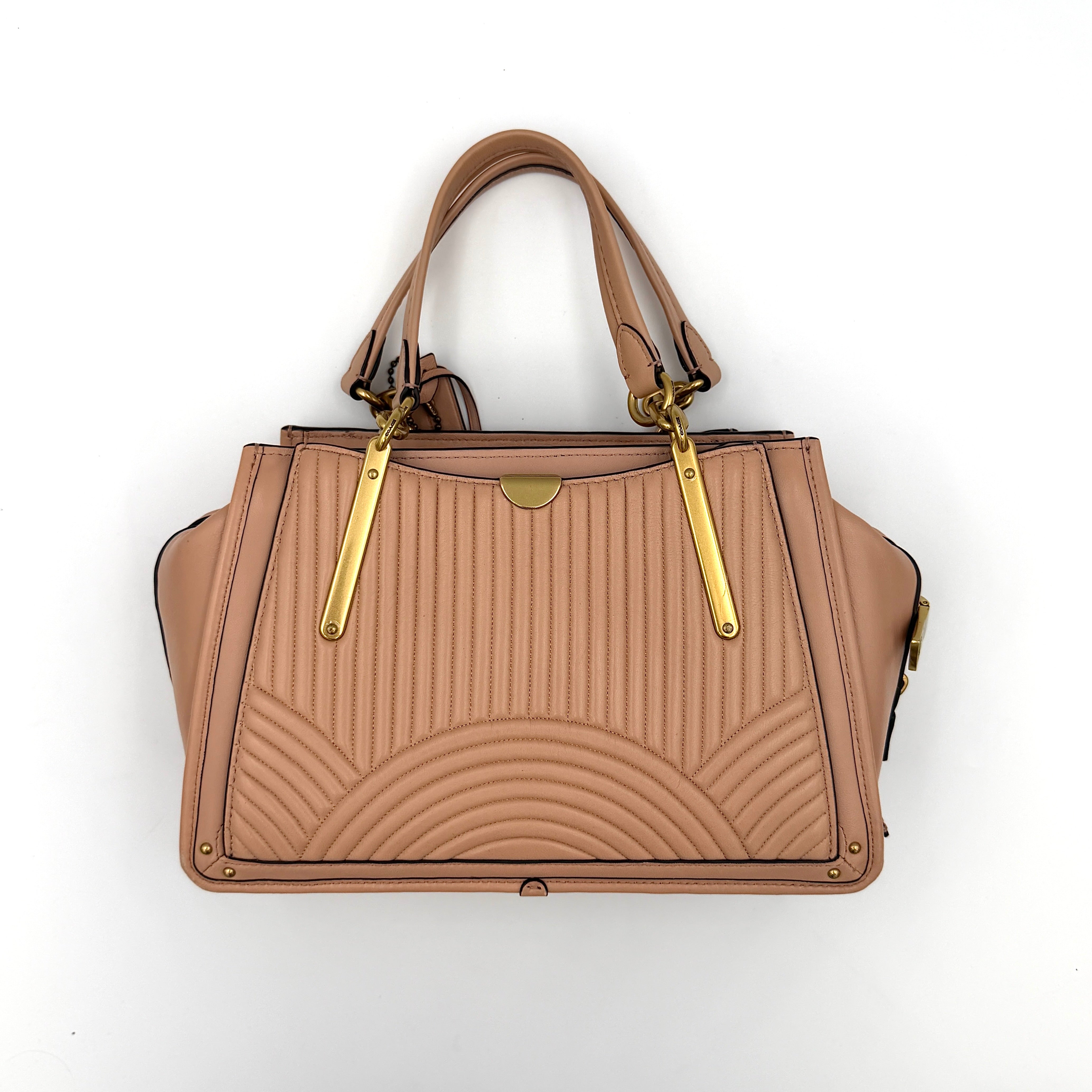 Coach Dreamer 27 handbag in nude pink leather with Deco quilting, gold rivets, and detachable strap, displayed elegantly on a plain background.