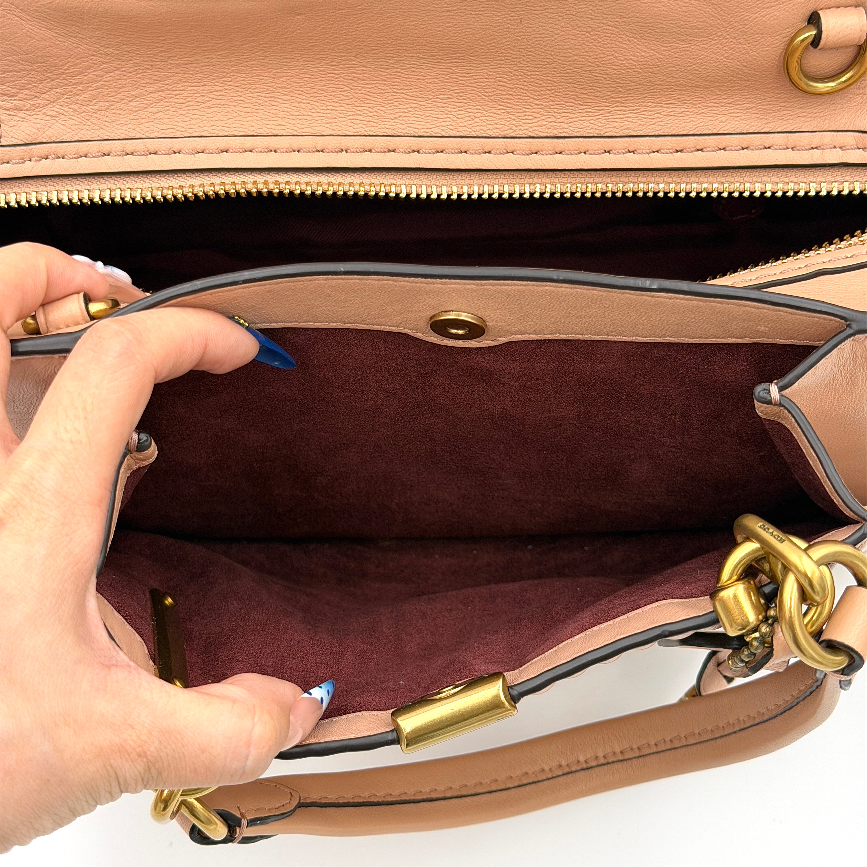 Coach Dreamer 27 handbag in nude pink leather with Deco quilting, gold rivets, and detachable strap, displayed elegantly on a plain background.