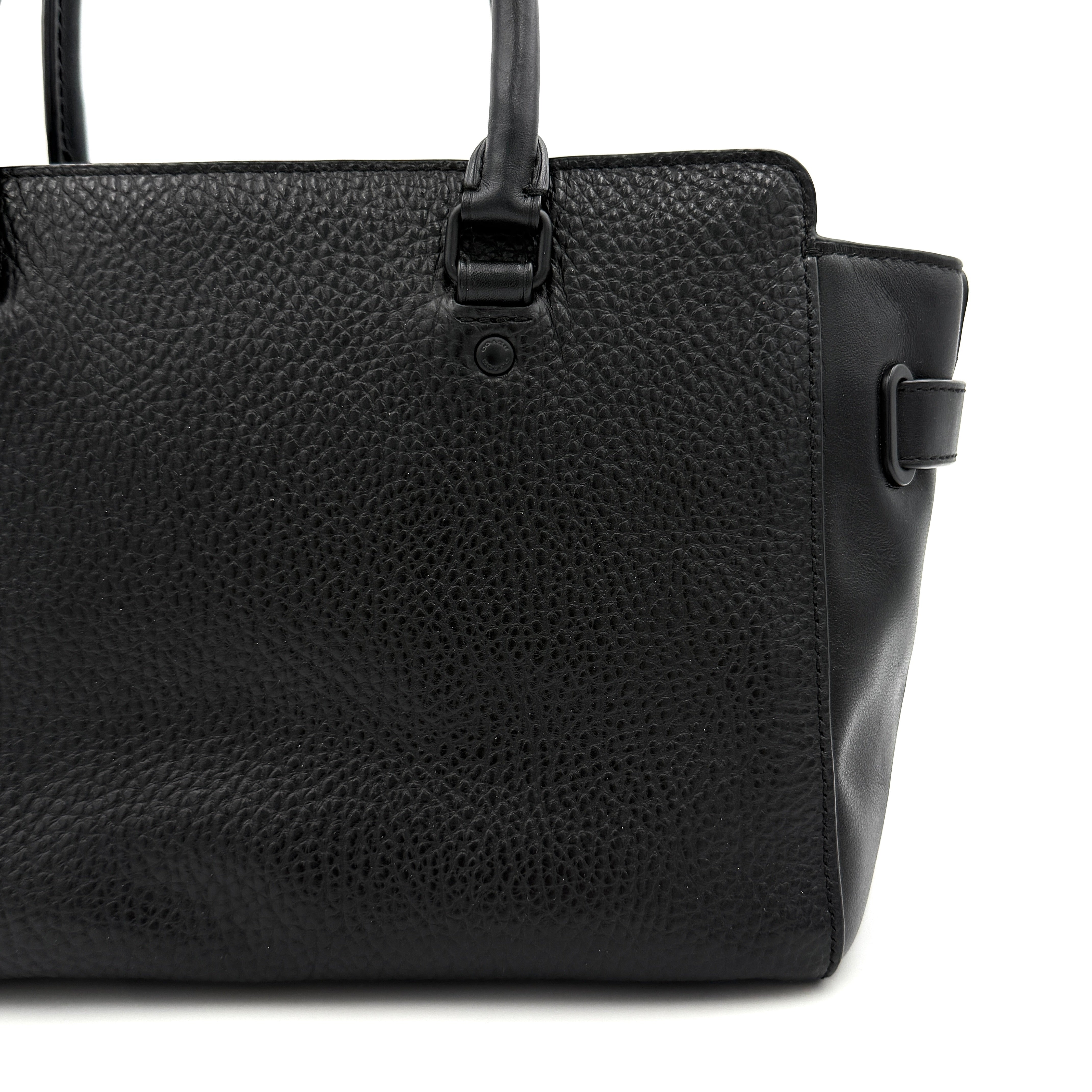 Coach Blake Carryall 25 bag in black pebbled leather with dual top handles, detachable strap, and front turnlock accents.