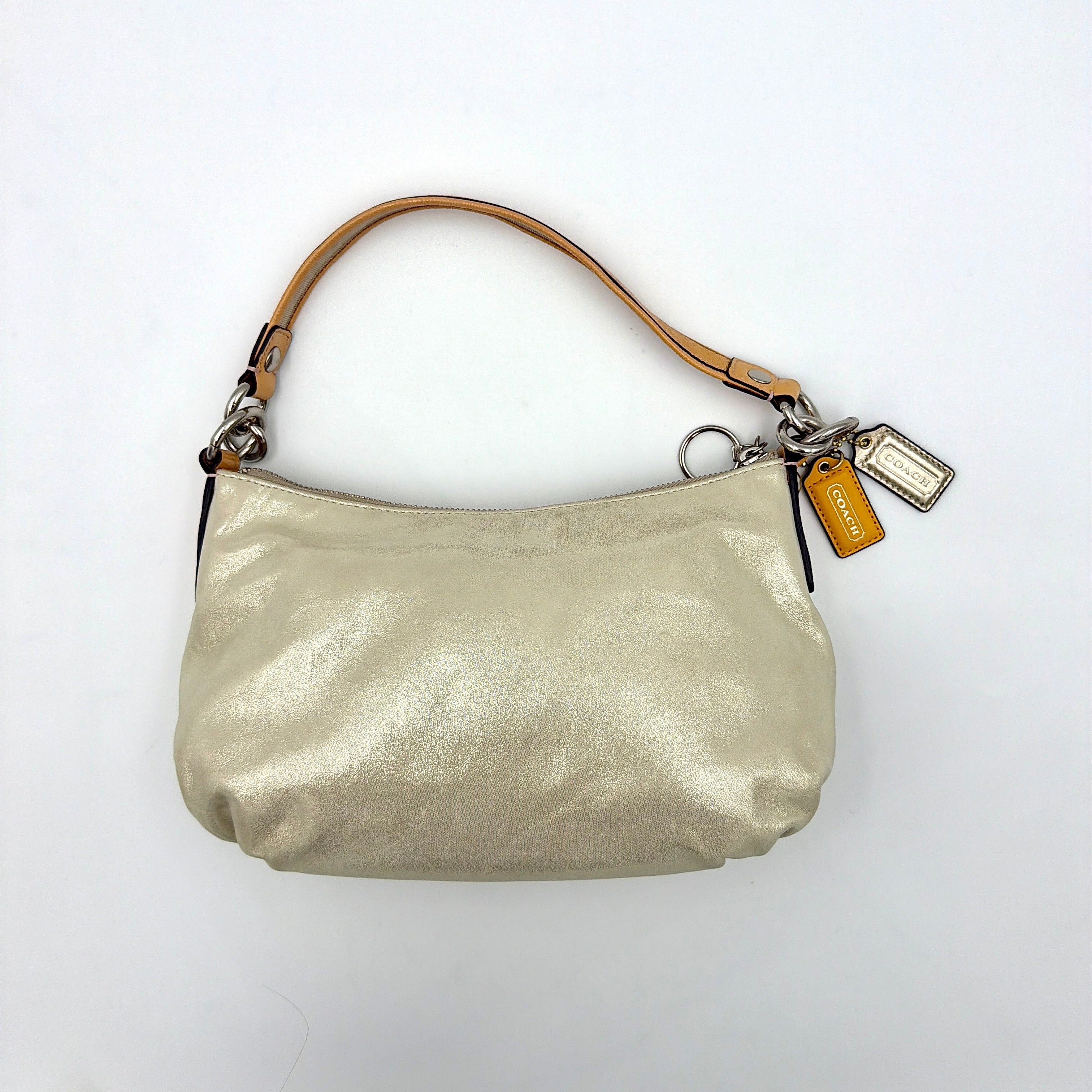 Coach Poppy Sparkle Groovy bag in cream with tan trim, metallic plaque, and detachable shoulder strap displayed alongside.