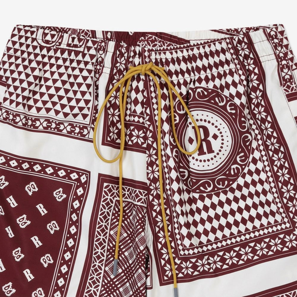 Rhude maroon and white swim shorts with a card print pattern and yellow drawstring, presented flat.