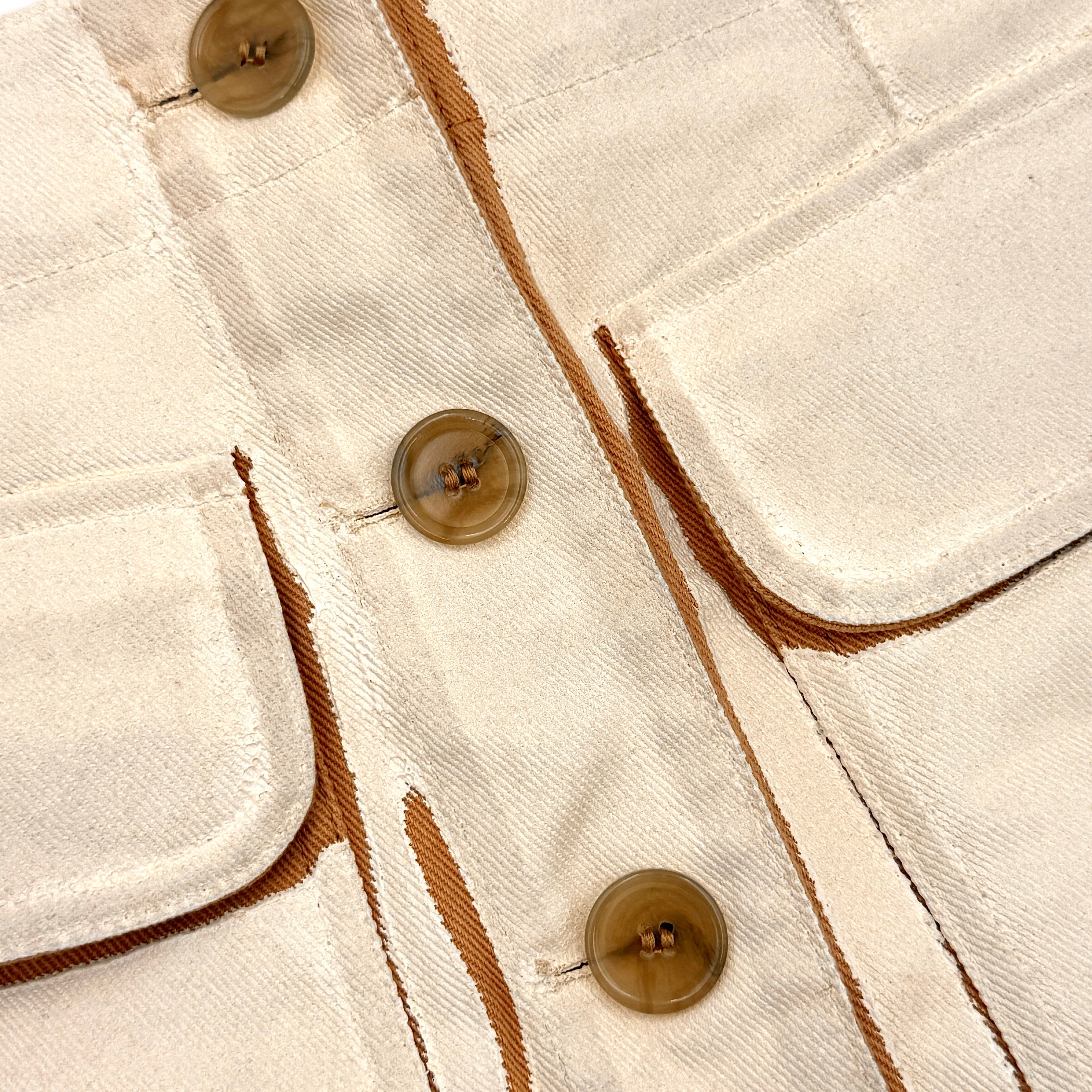 Acne Studios cream and tan cotton drill mini skirt with oversized flap pockets and front button closure, styled flat.