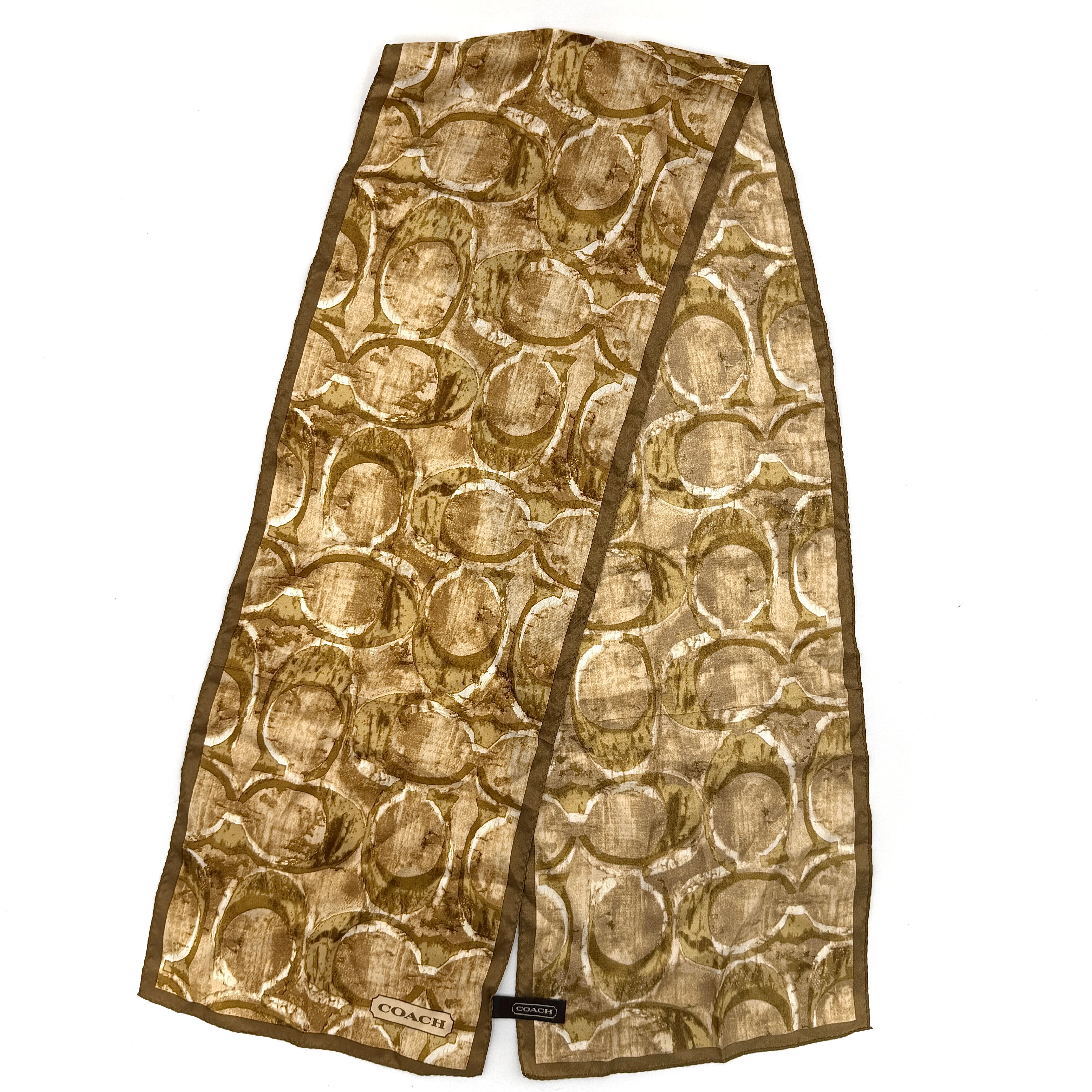 Coach silk scarf in rich brown tones, featuring an oversized signature monogram pattern and solid brown trim.