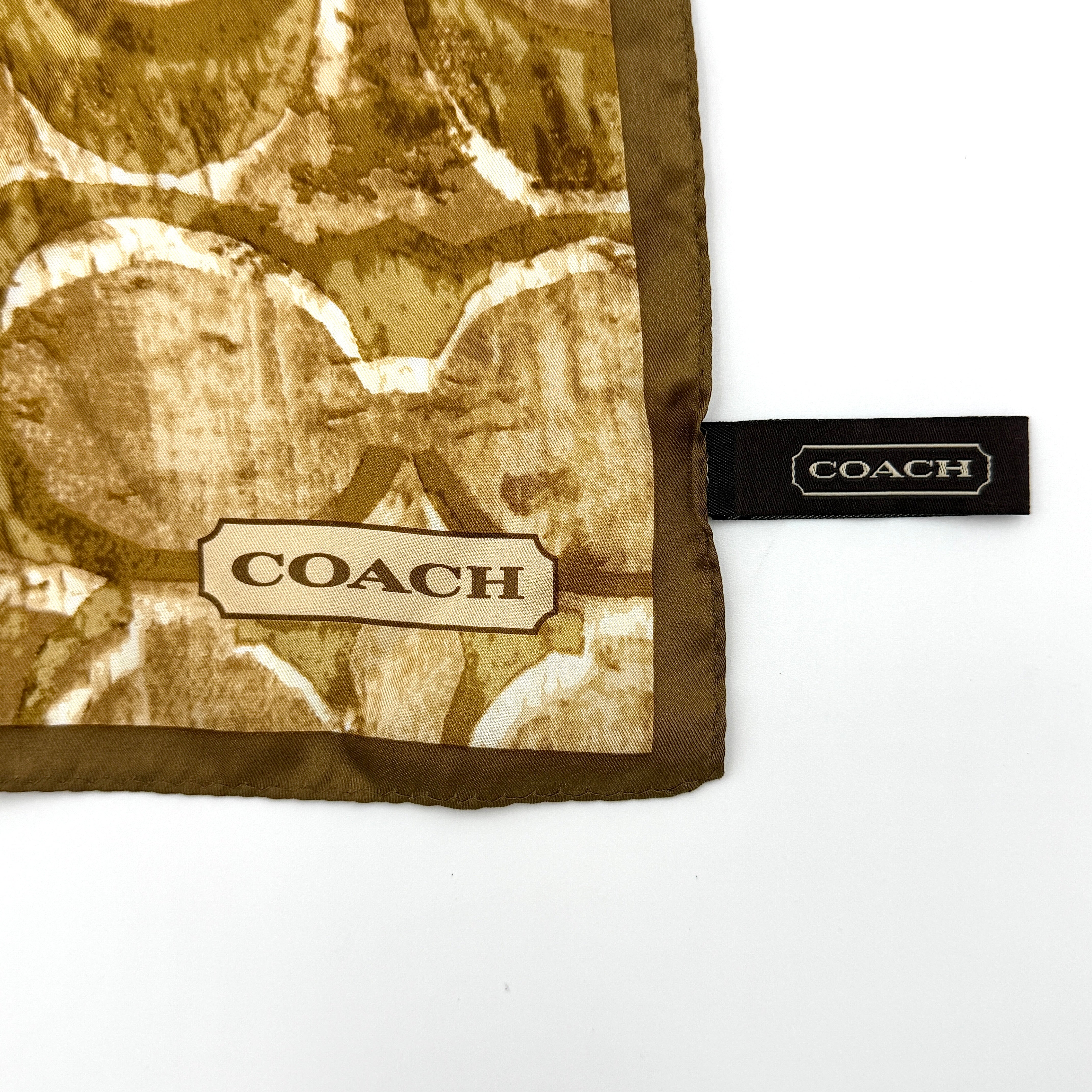 Coach silk scarf in rich brown tones, featuring an oversized signature monogram pattern and solid brown trim.