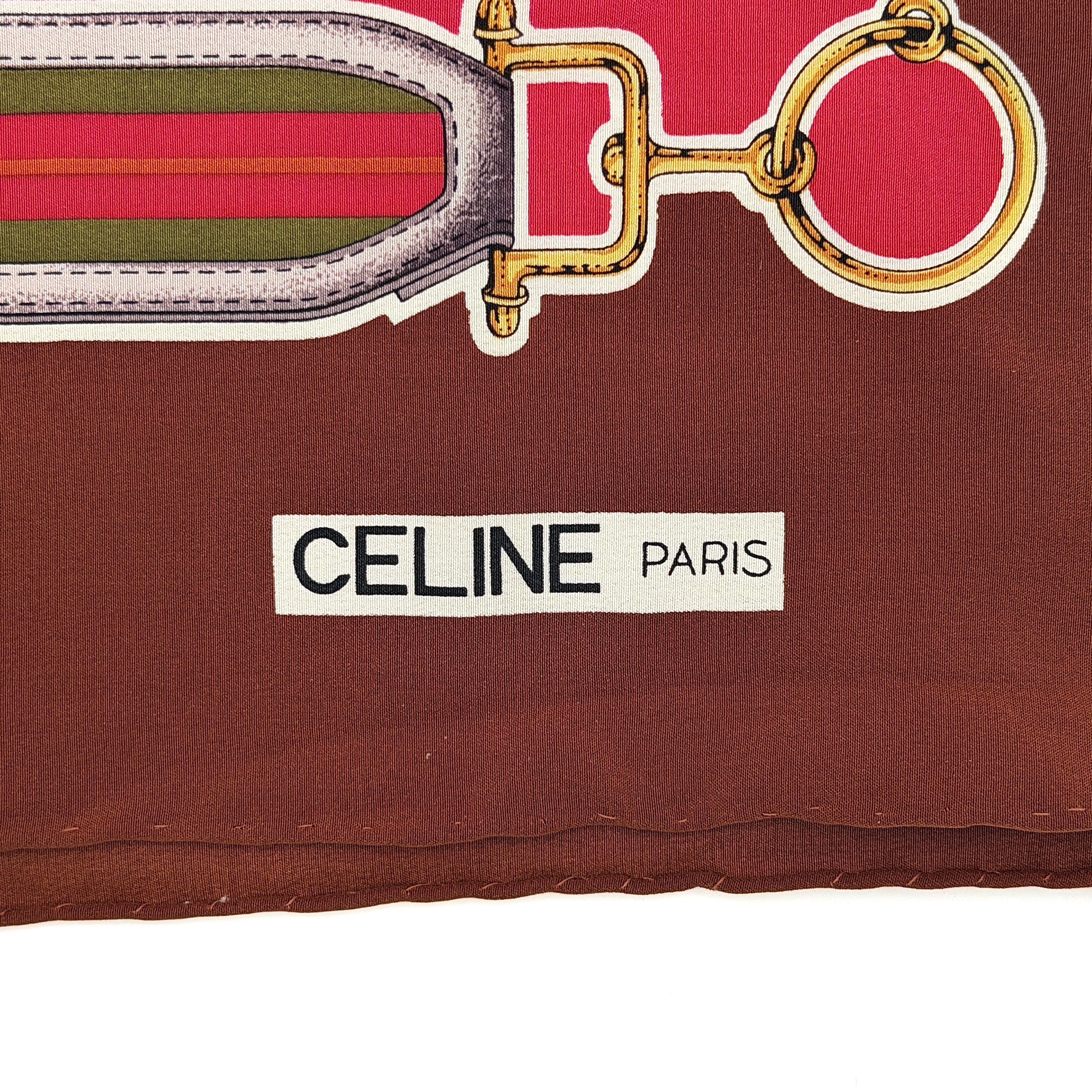 Celine silk scarf in raspberry pink, periwinkle blue, and brown with illustrated buckle and strap motifs.