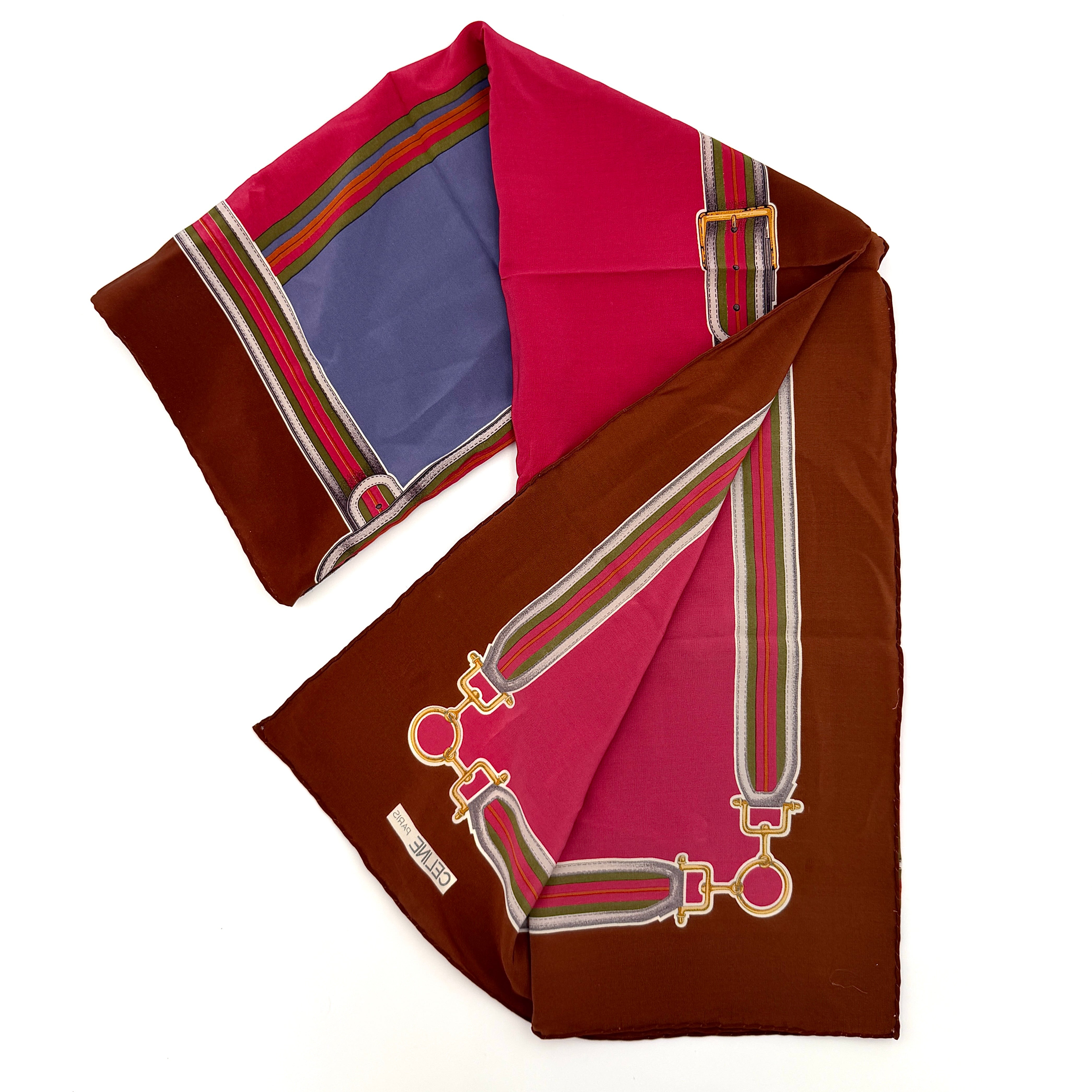 Celine silk scarf in raspberry pink, periwinkle blue, and brown with illustrated buckle and strap motifs.