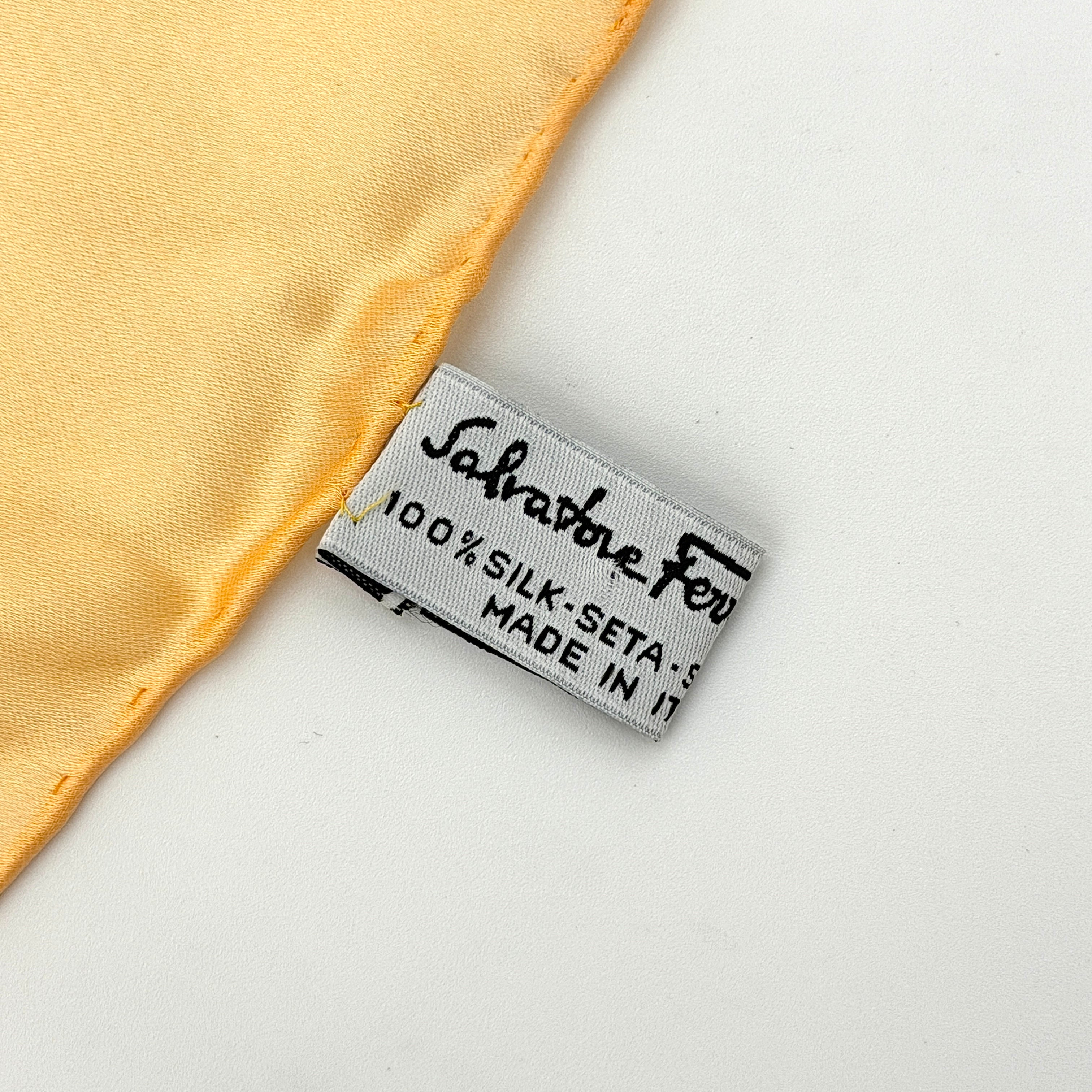 An orange Salvatore Ferragamo silk scarf with pastel floral print displayed in a gentle drape.