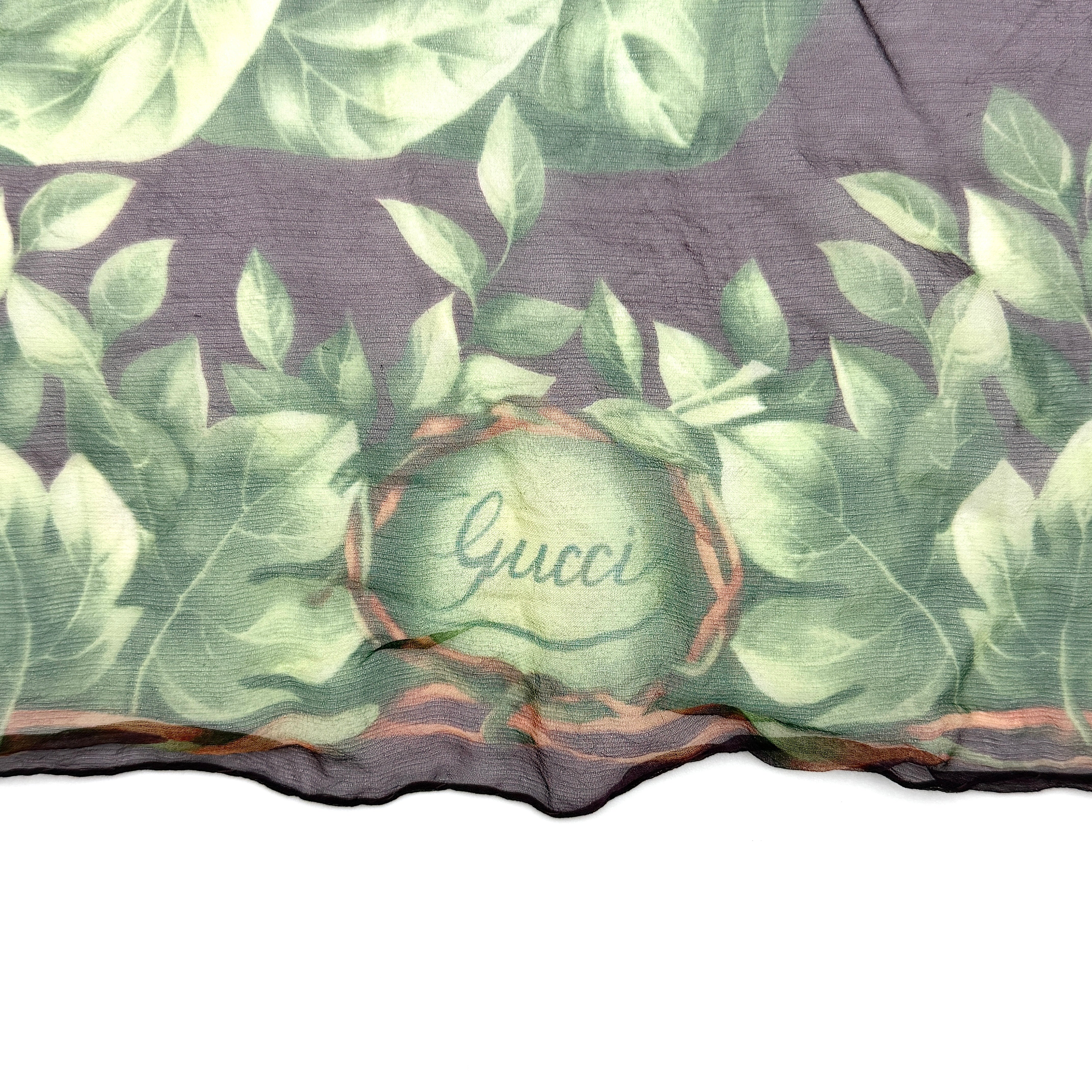 Gucci silk scarf adorned with artistic multicolour floral bouquets and leafy green border, elegantly draped to showcase its lightweight, sheer texture.