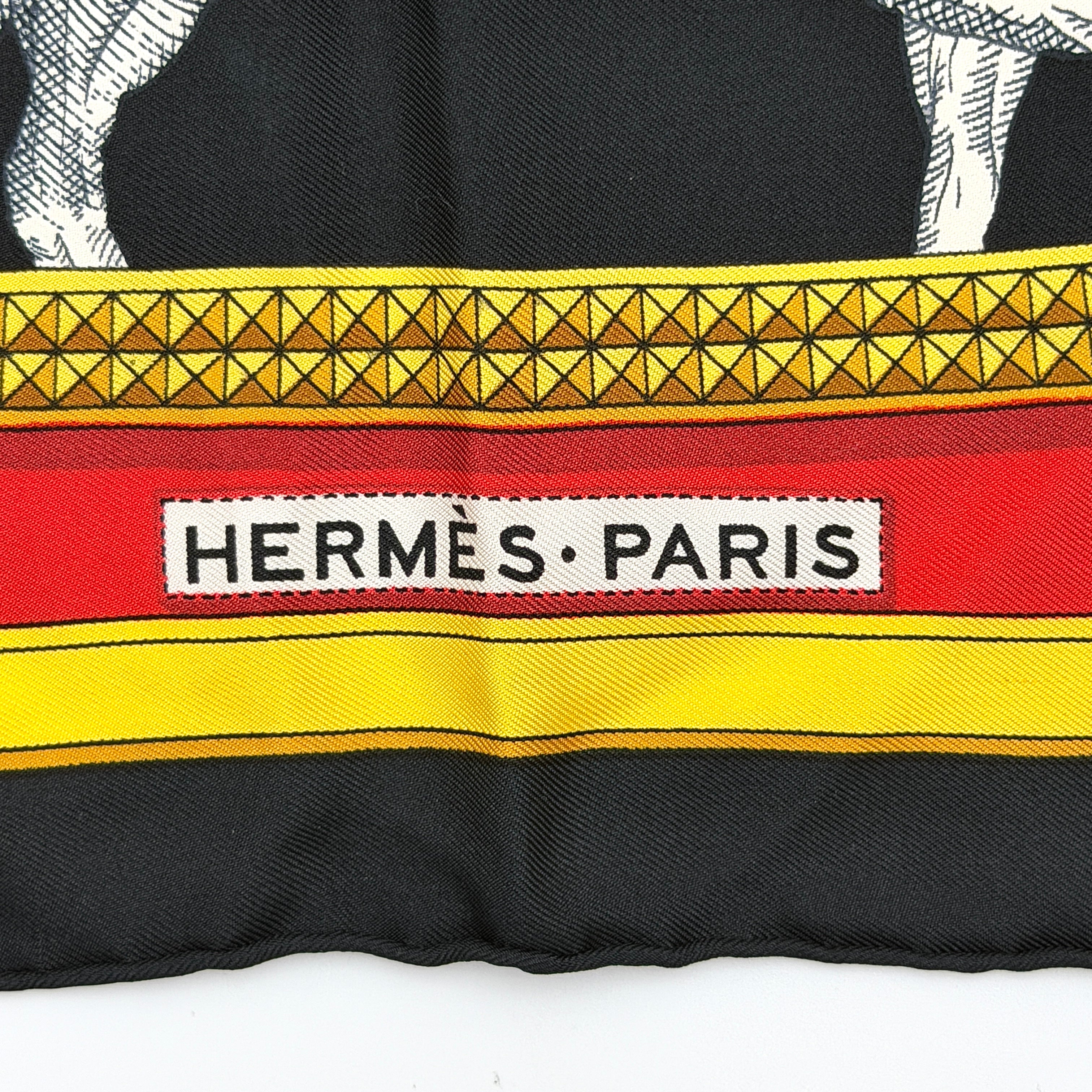 Hermès Grand Apparat silk scarf, featuring an ornate equestrian motif in rich red, gold, and black, elegantly folded to showcase its intricate print.