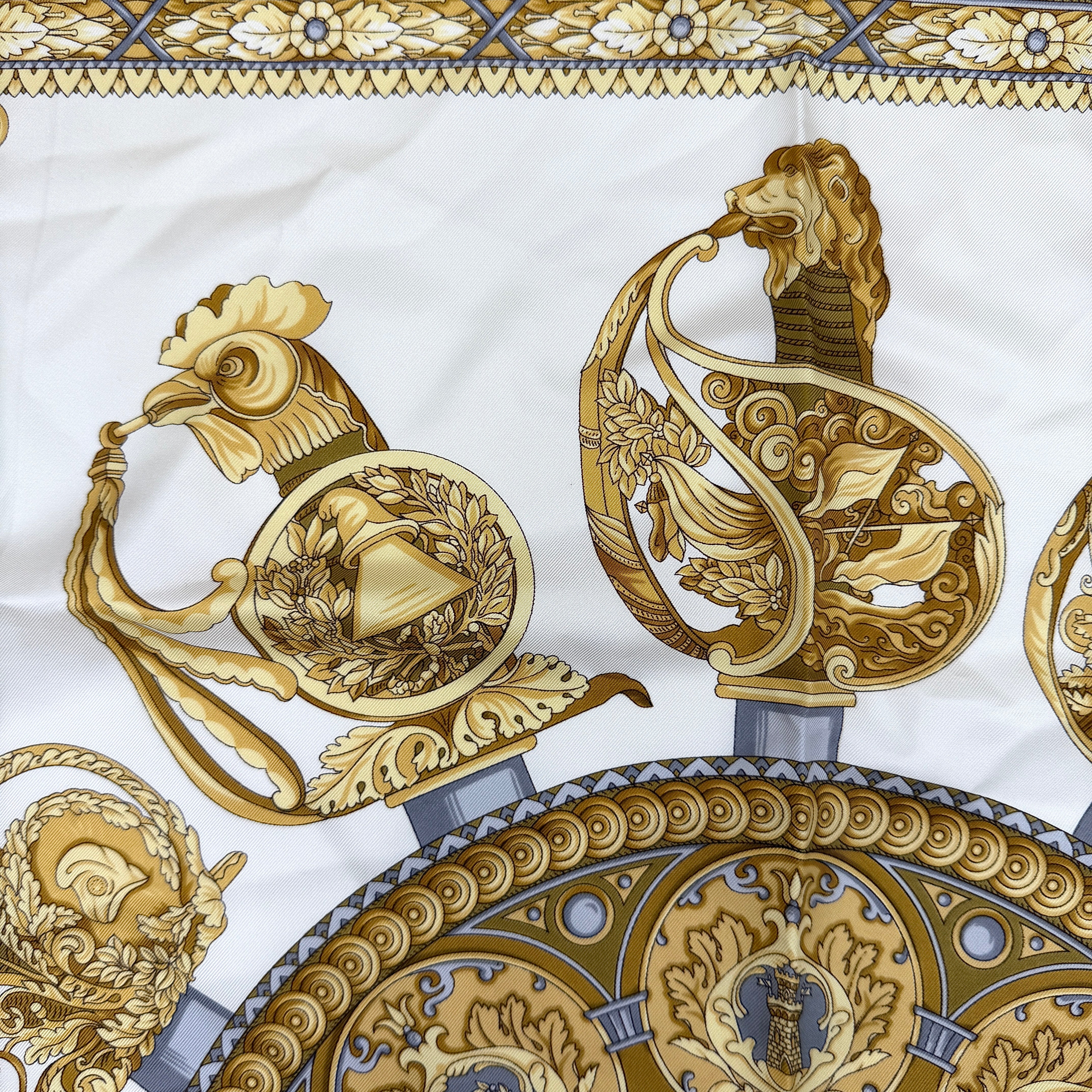 Gucci silk scarf in gold and white, featuring an intricate equestrian medallion design with ornate sabres and classical borders.
