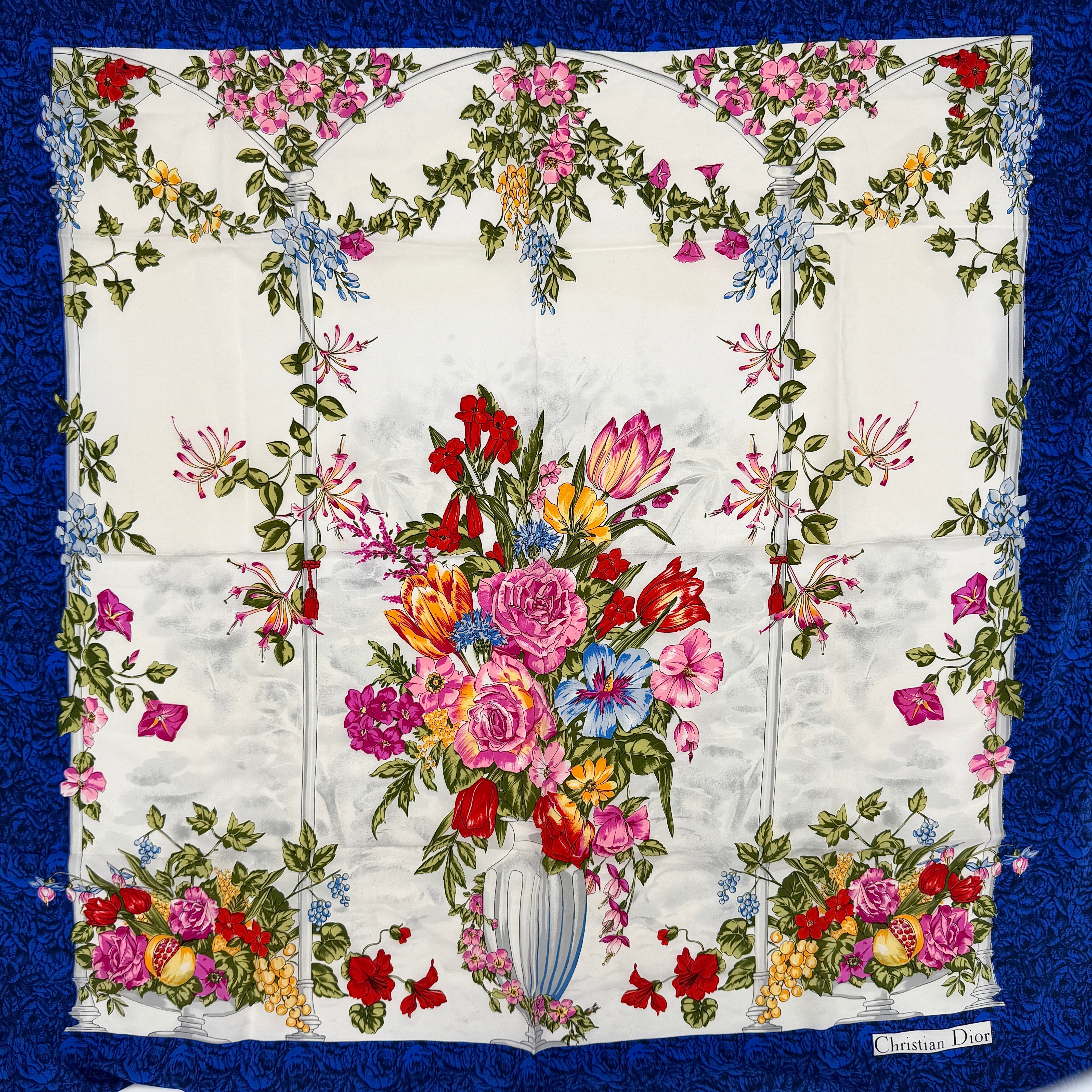 Dior silk scarf featuring an ornate multicolour floral print with a deep blue border.