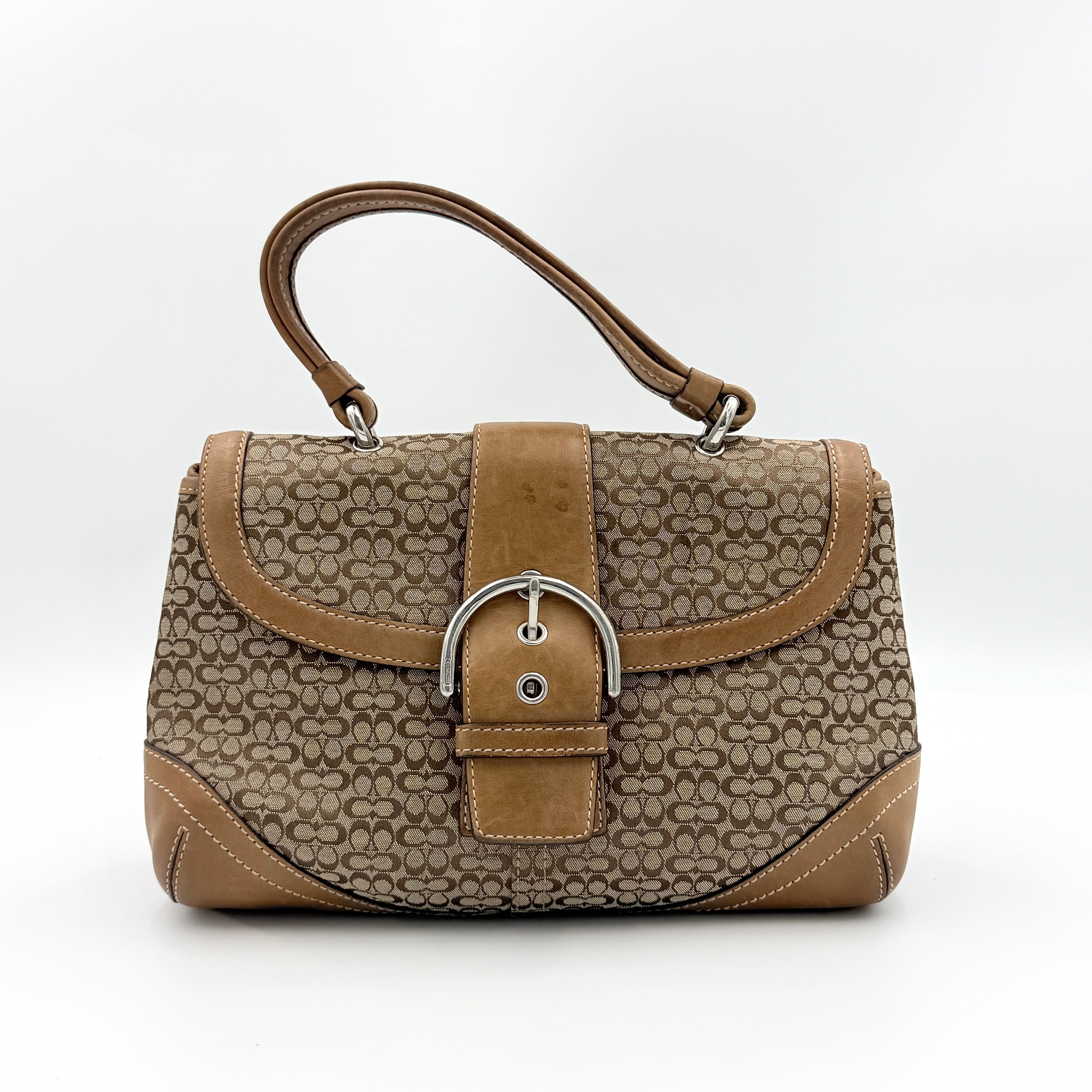 Coach Signature Soho shoulder bag in beige and tan jacquard with leather trim and silver D-ring buckle, shown against a white background.