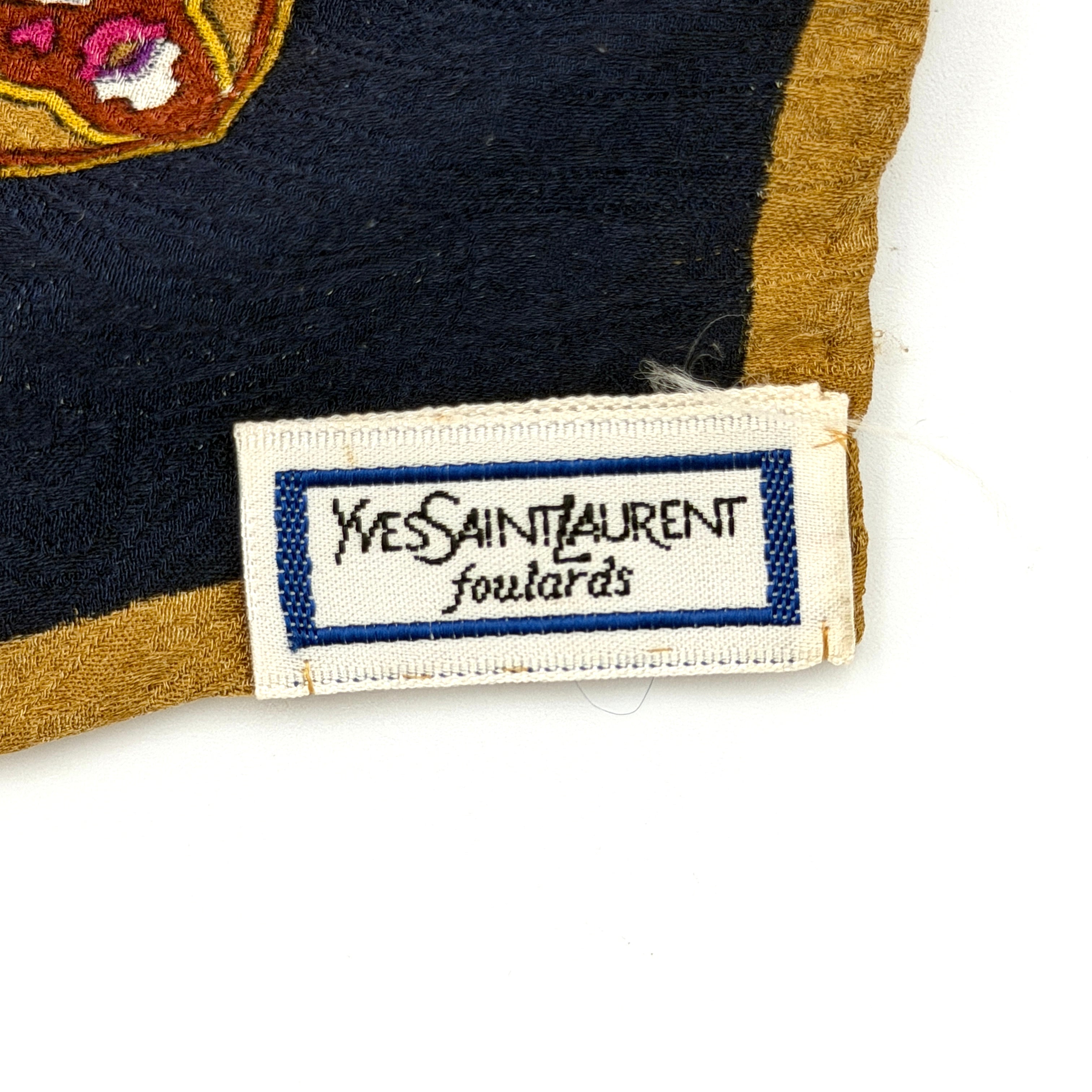 A Saint Laurent cotton scarf in multicolour paisley, elegantly folded to reveal its intricate pattern and ochre border.