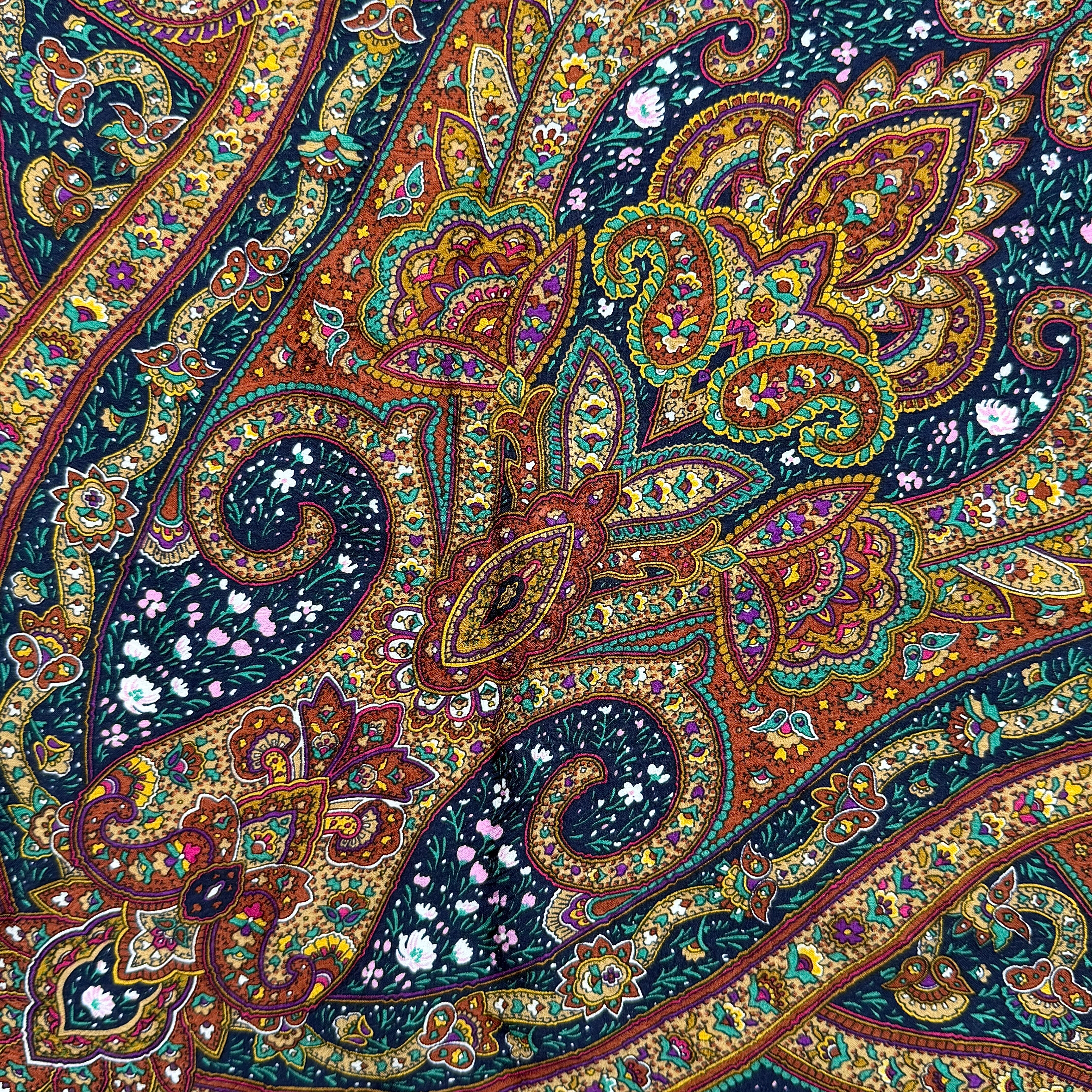 A Saint Laurent cotton scarf in multicolour paisley, elegantly folded to reveal its intricate pattern and ochre border.