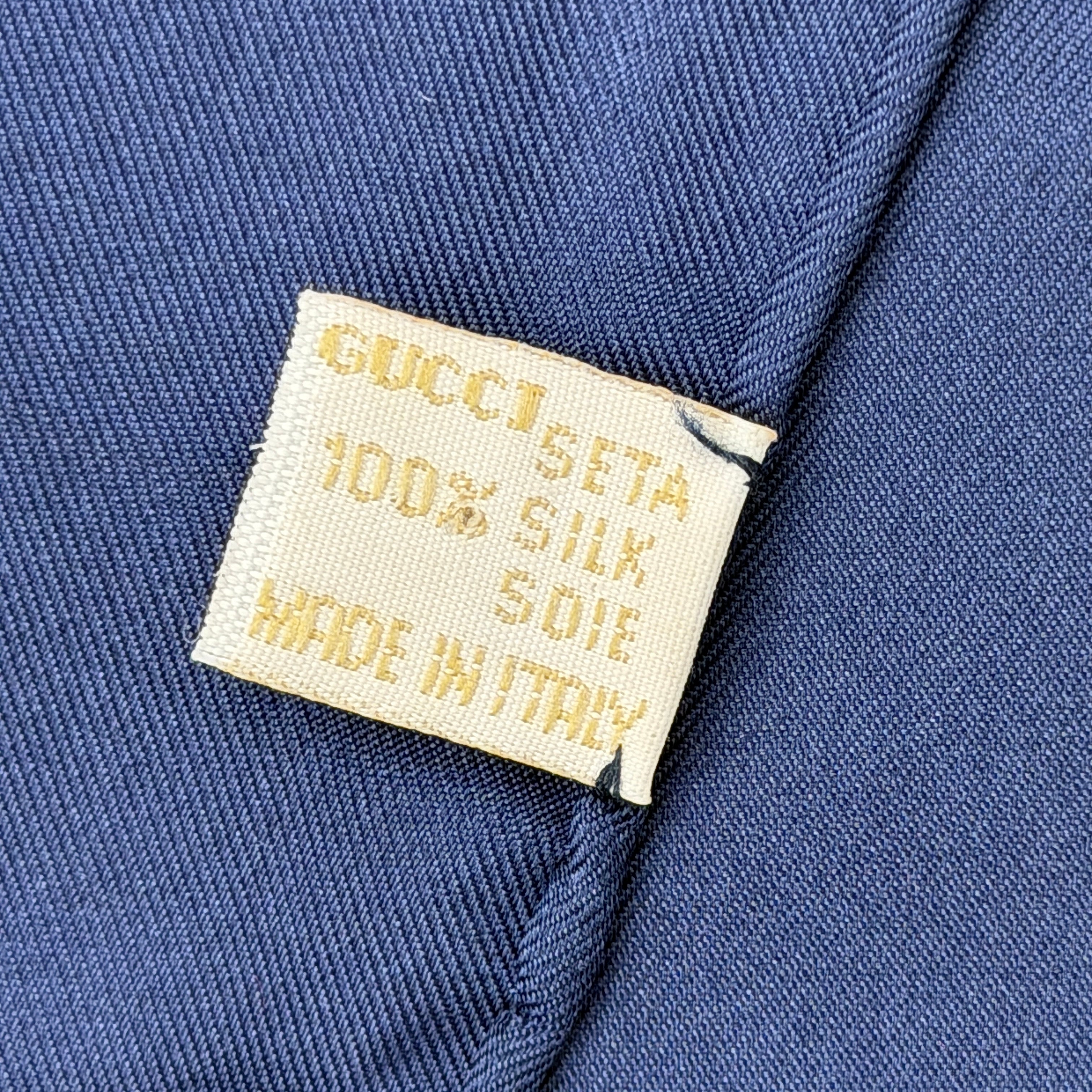 Gucci silk scarf with equestrian horsebit print, navy borders, and large GG logo displayed against a white background.